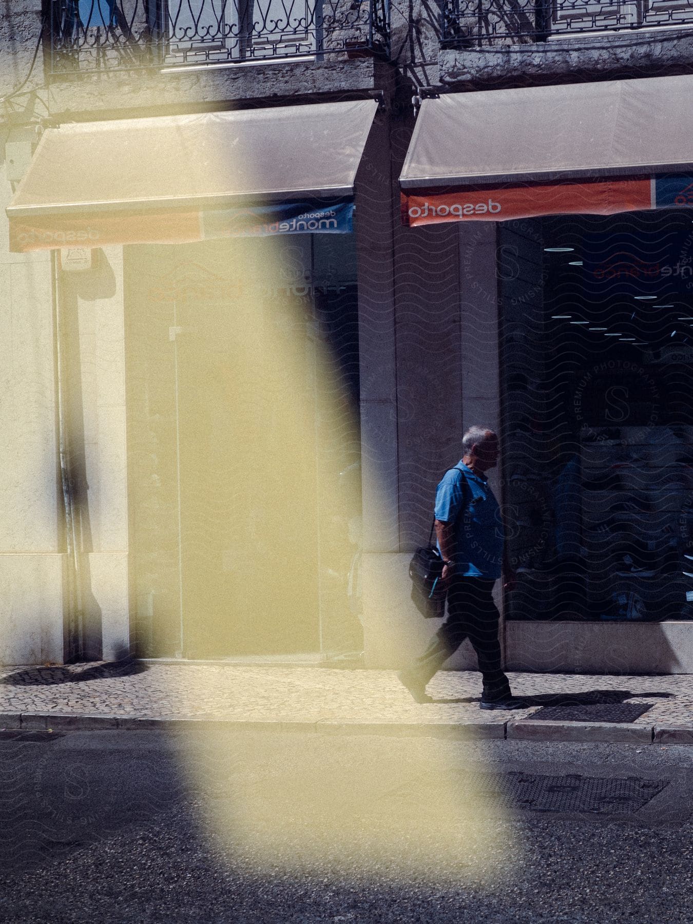 Balding man in blue shirt walks past shoe store with briefcase