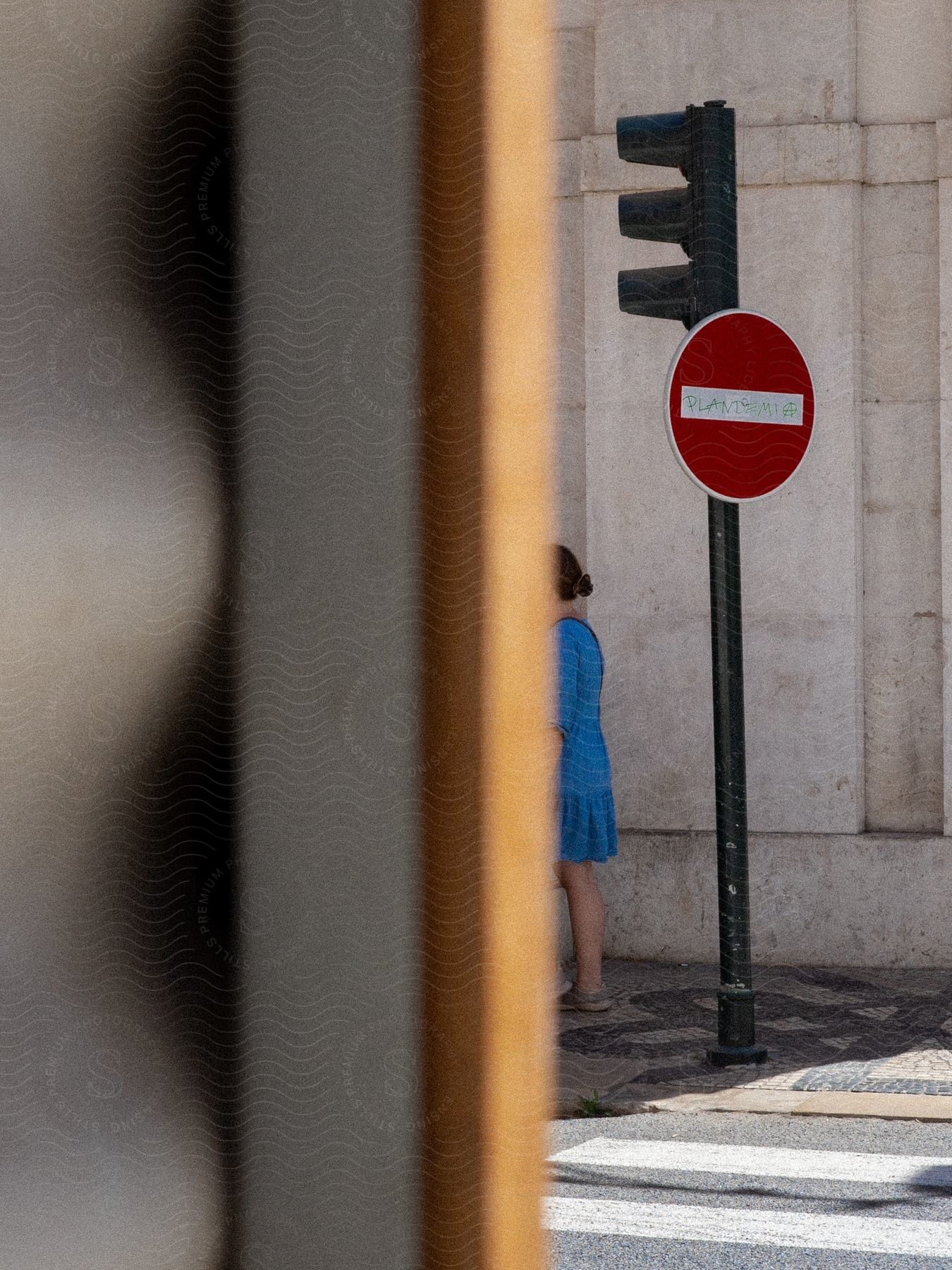 Woman wearing a blue dress walking on the streets seen from the inside of a window or door