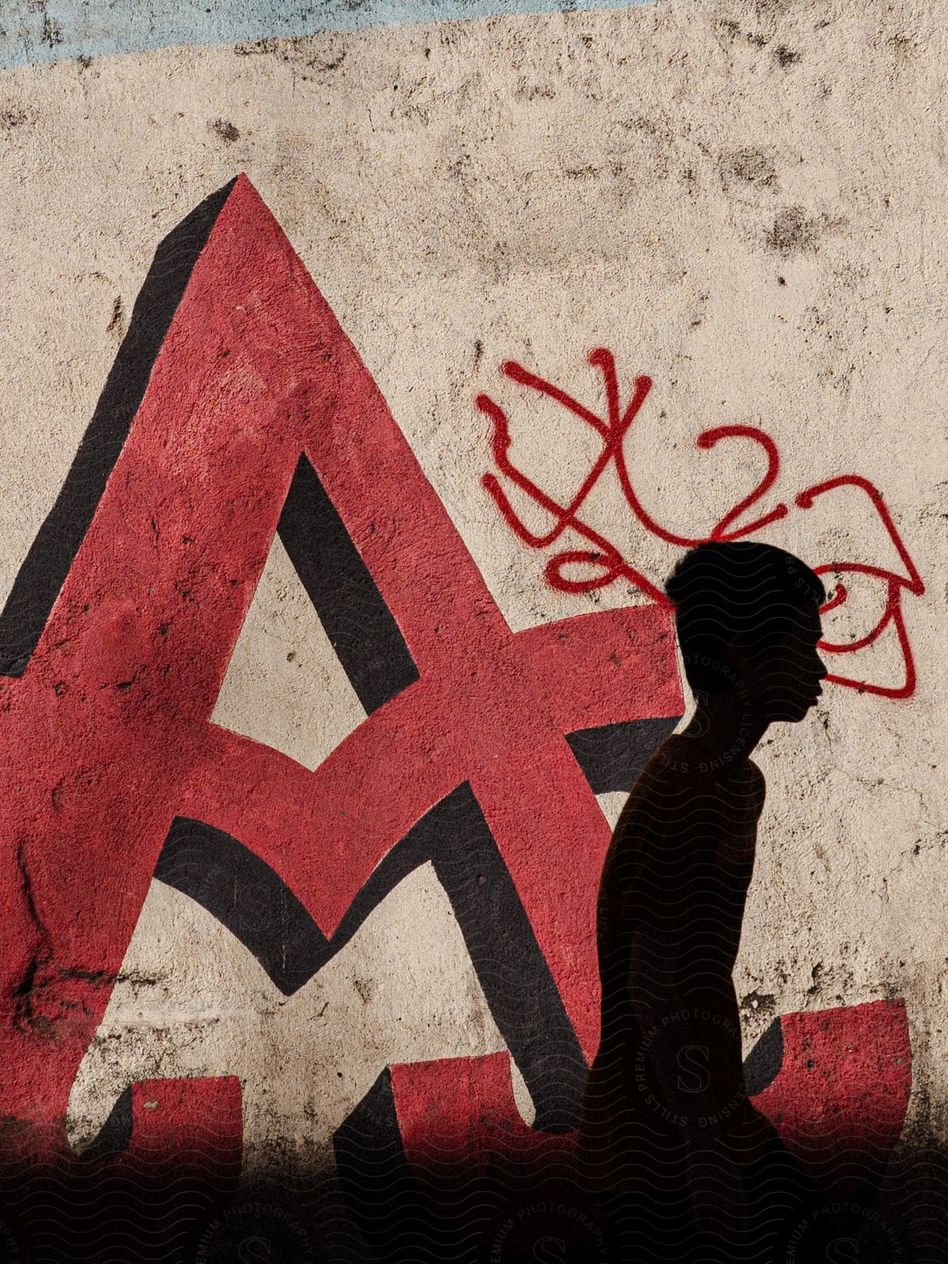 Stock photo of red a sign painting on wall with darkshaded boy walking