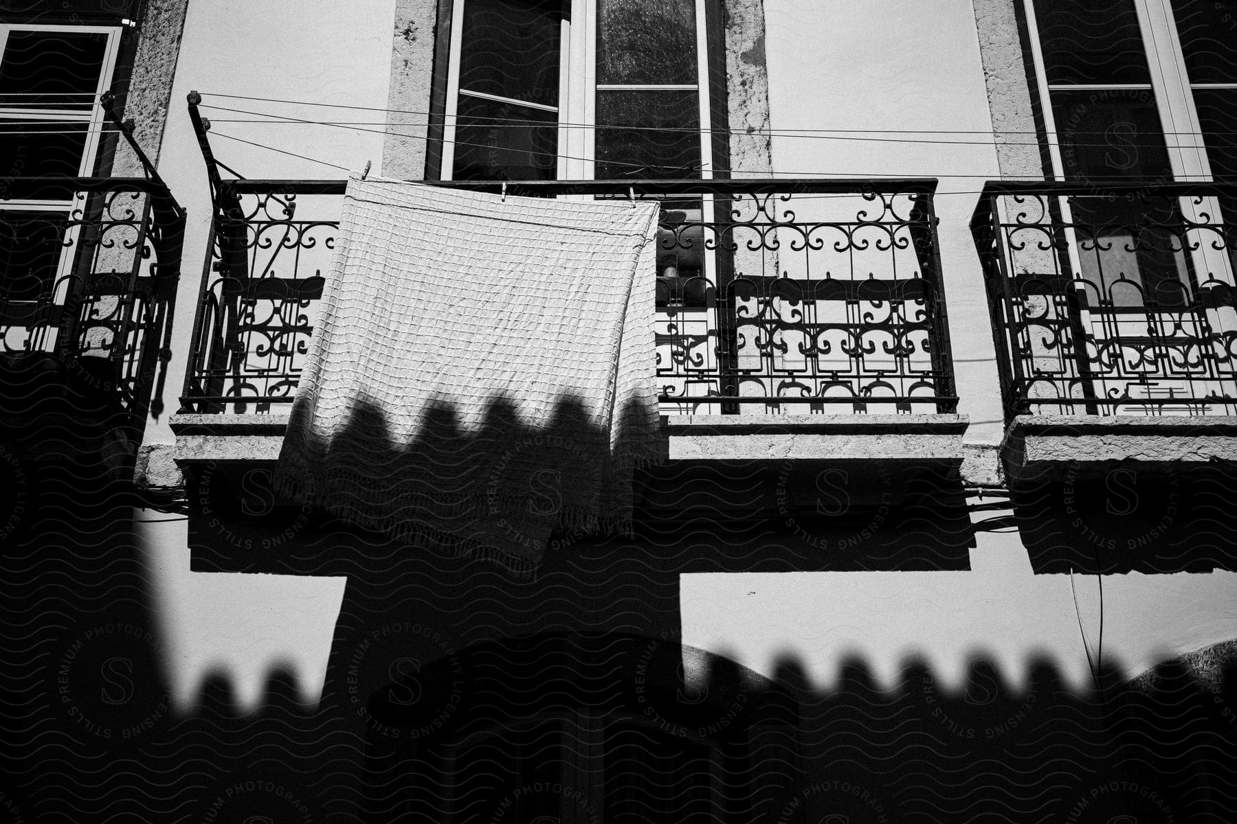 Black and white photo of a building with a towel hanging to dry next to a window