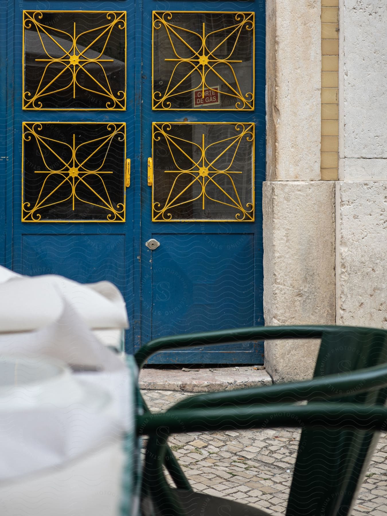 A chair from a coffee shop stands in front of the door to an old apartment building