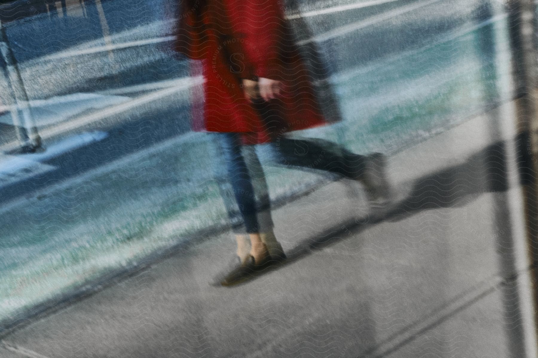 A woman in a red coat walks along a sidewalk next to a street