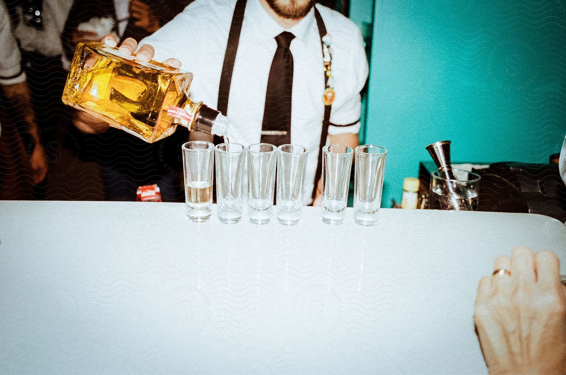 Stock photo of a bartender pouring liquor into shot glasses