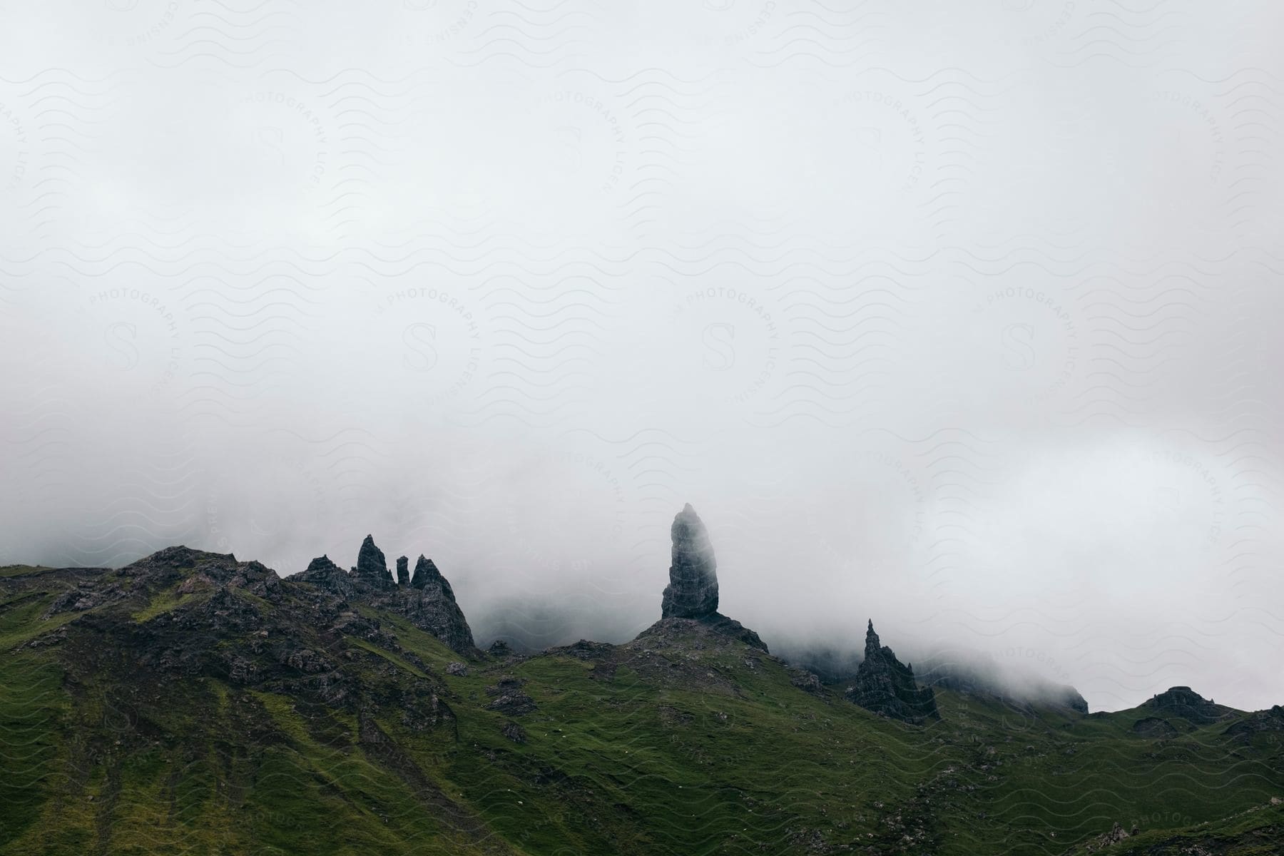 Rock formation on a grassy foggy mountain