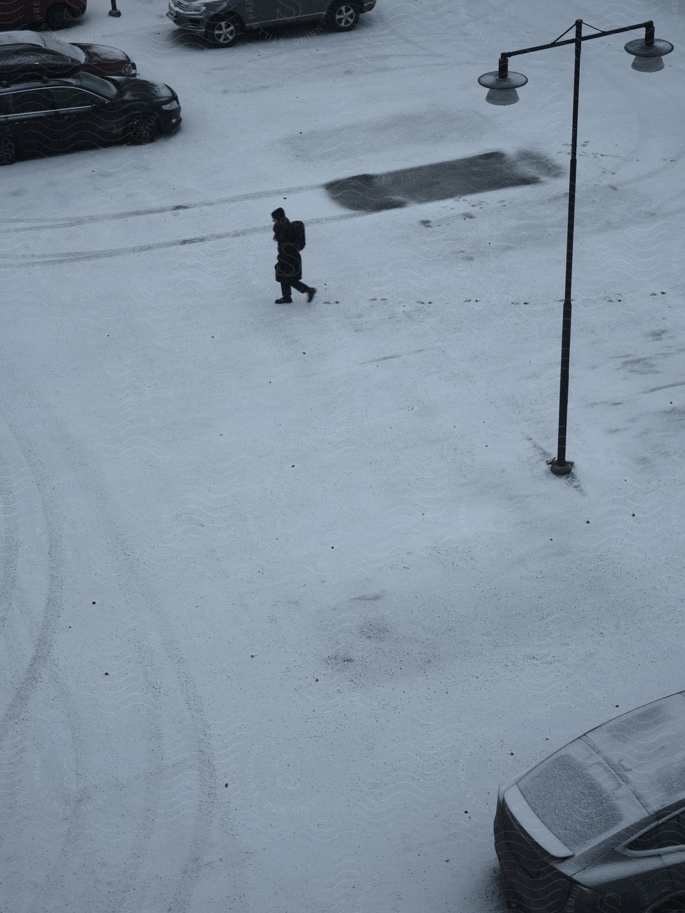 A person crossing a snowy road on a city street