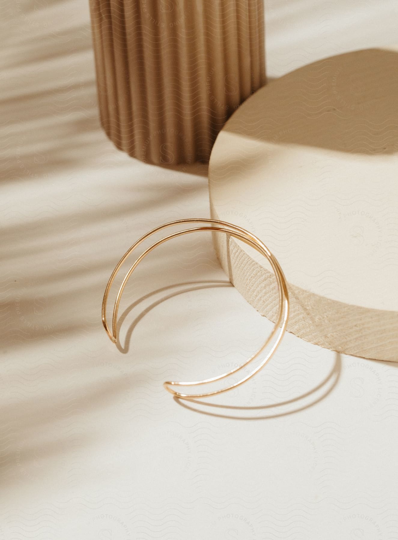 A gold cuff bracelet on a wooden display on top of a table