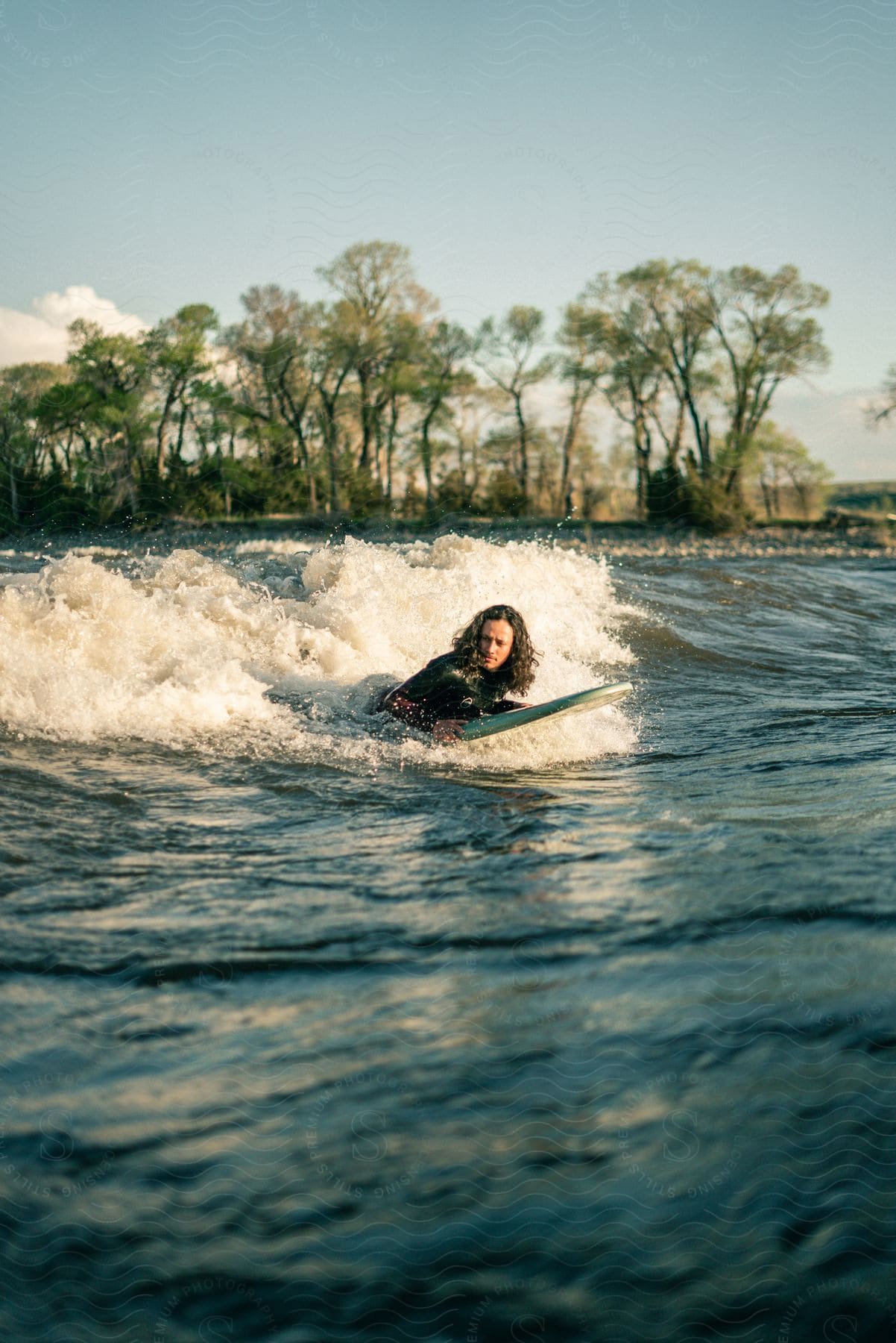 A surfer in a wetsuit rides a wave on a sunny day