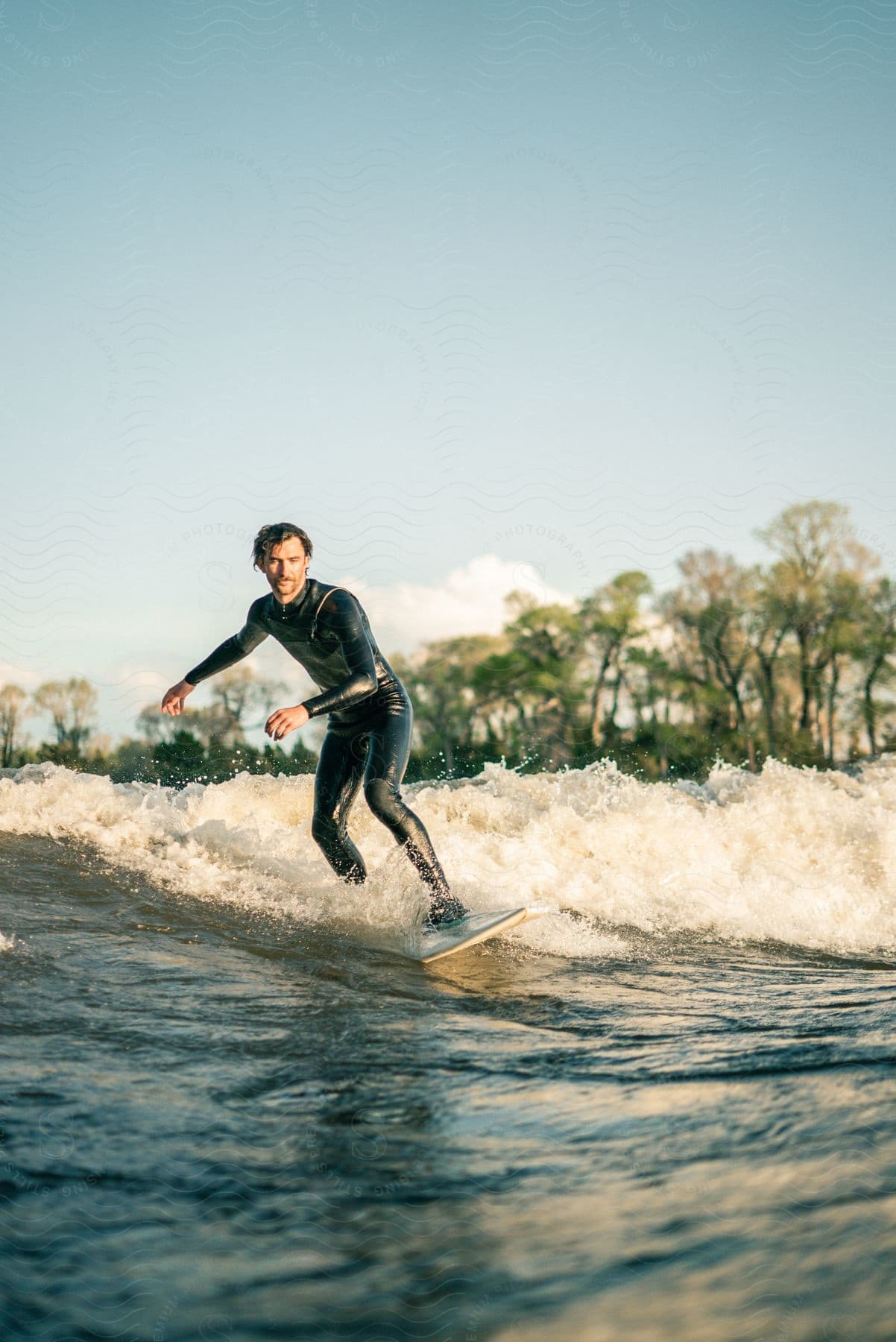 A man wearing a wet suit is surfing a wave as he rides into shore