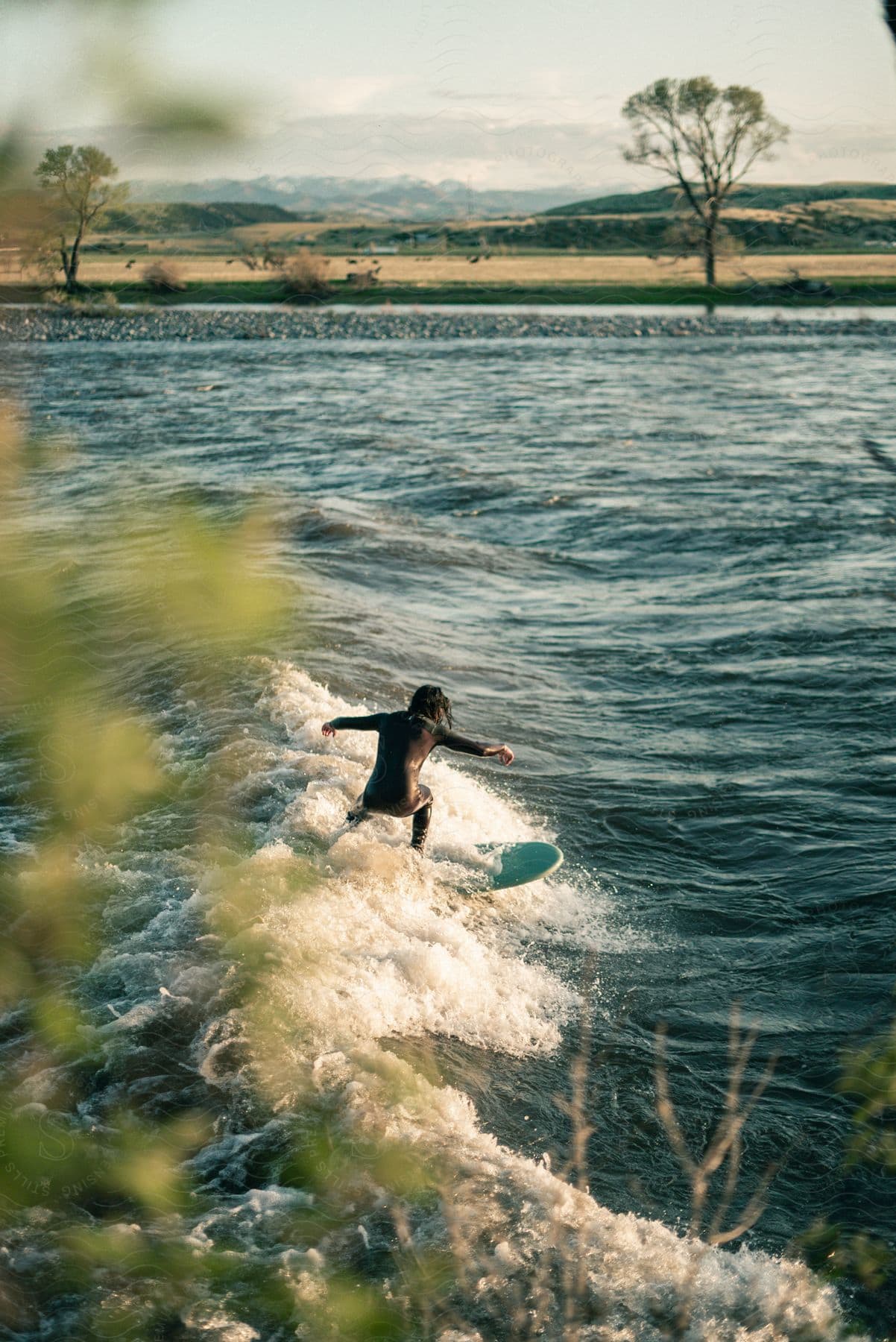 A man surfs a wave with his arms outstretched at dusk in montana