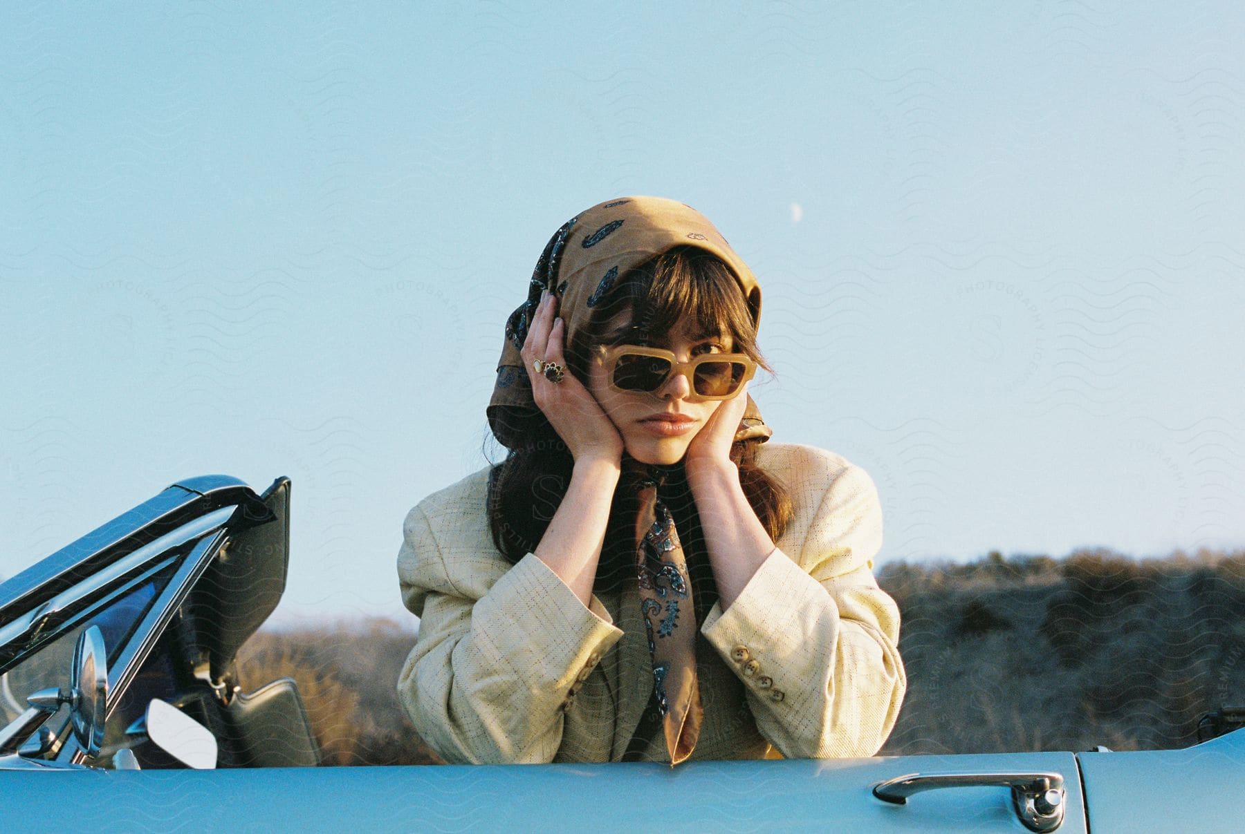 A happy woman wearing sunglasses in a car expressing excitement