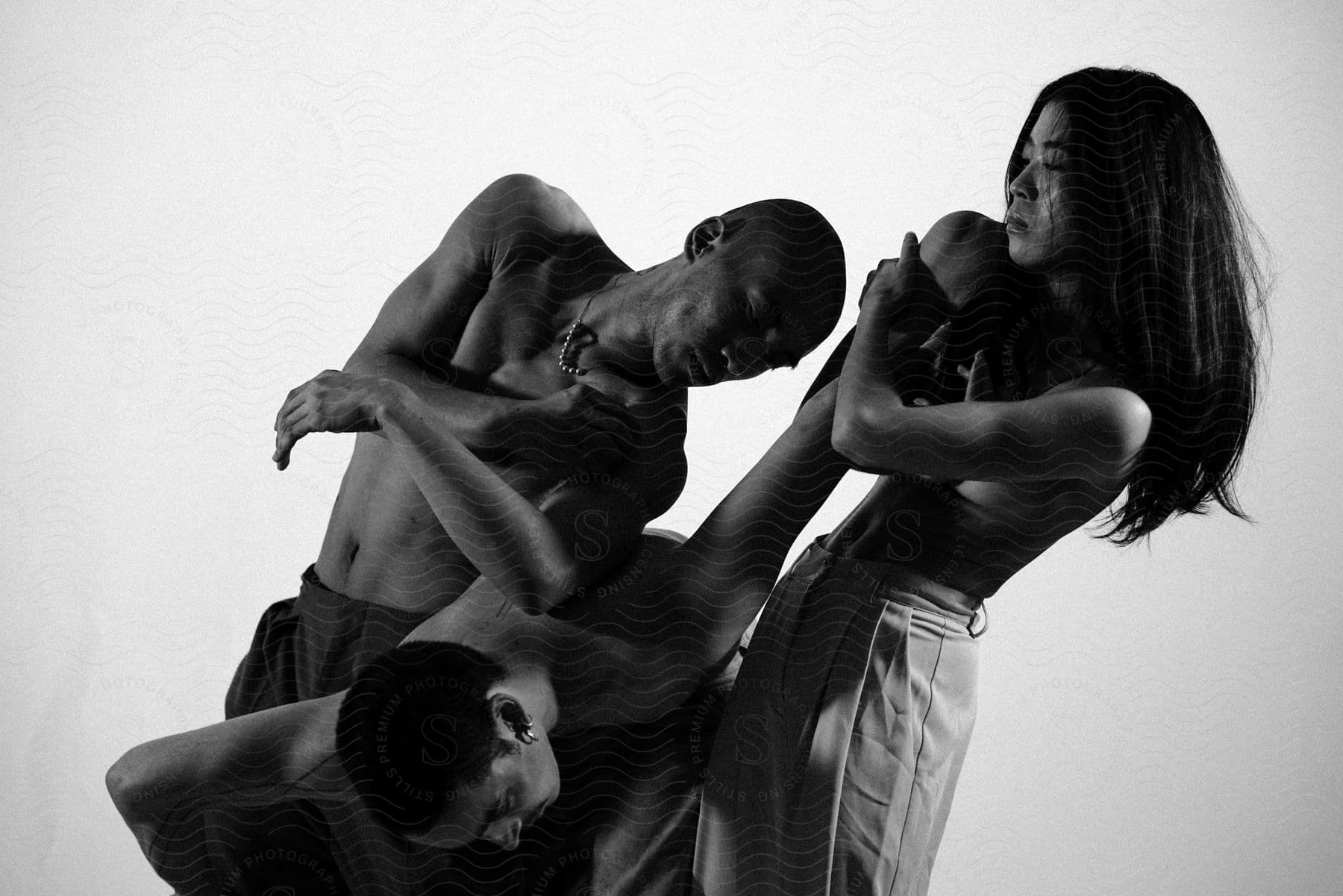 Three shirtless men in a pose with their arms entangled