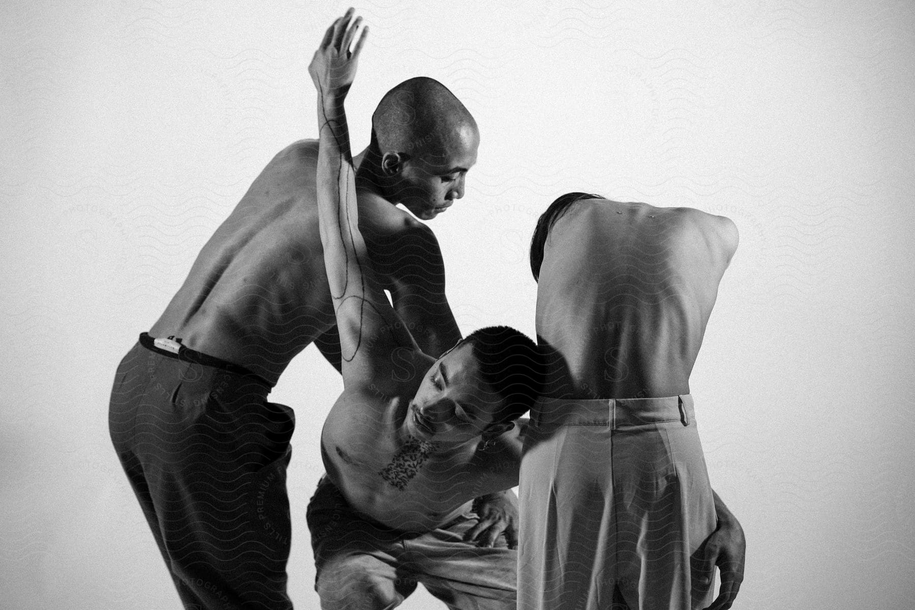 Three male dancers in various poses inside a white studio