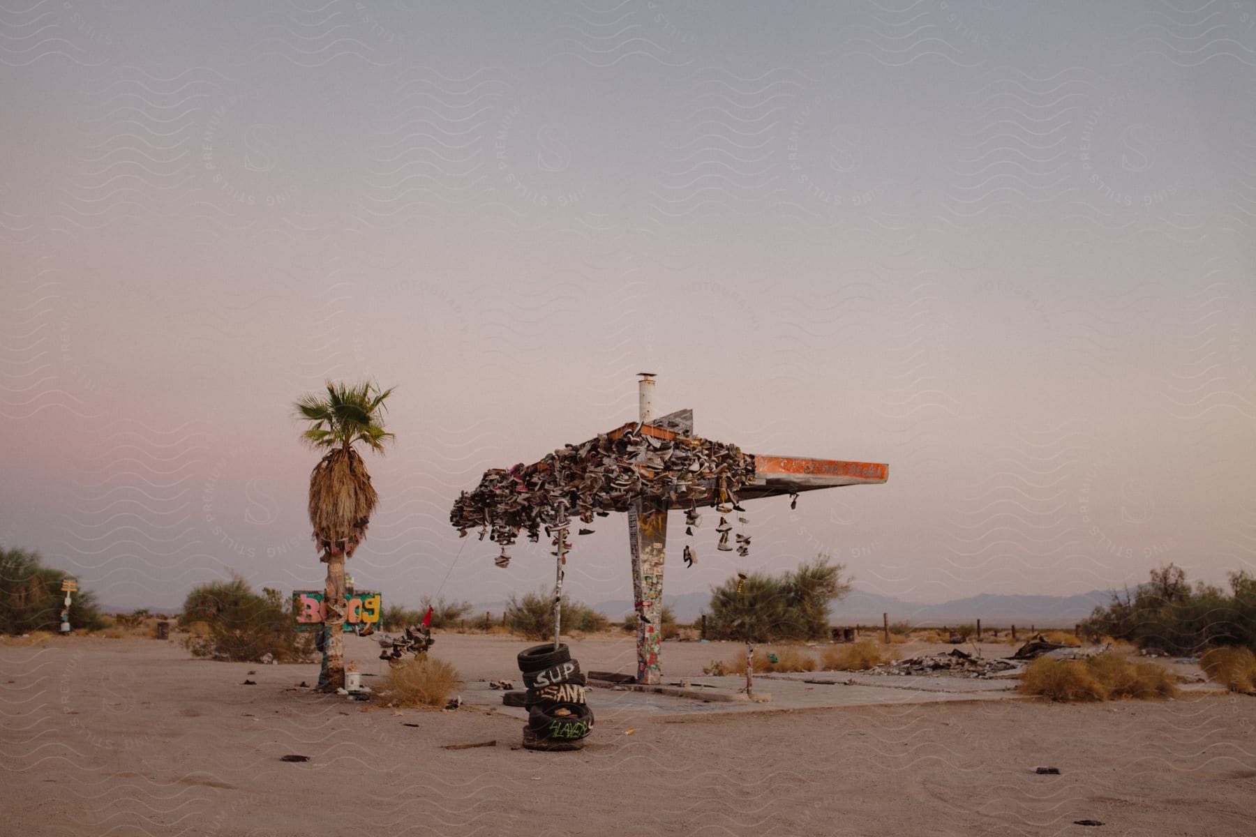 An abandoned shelter covered with shoes in a sandy landscape in california