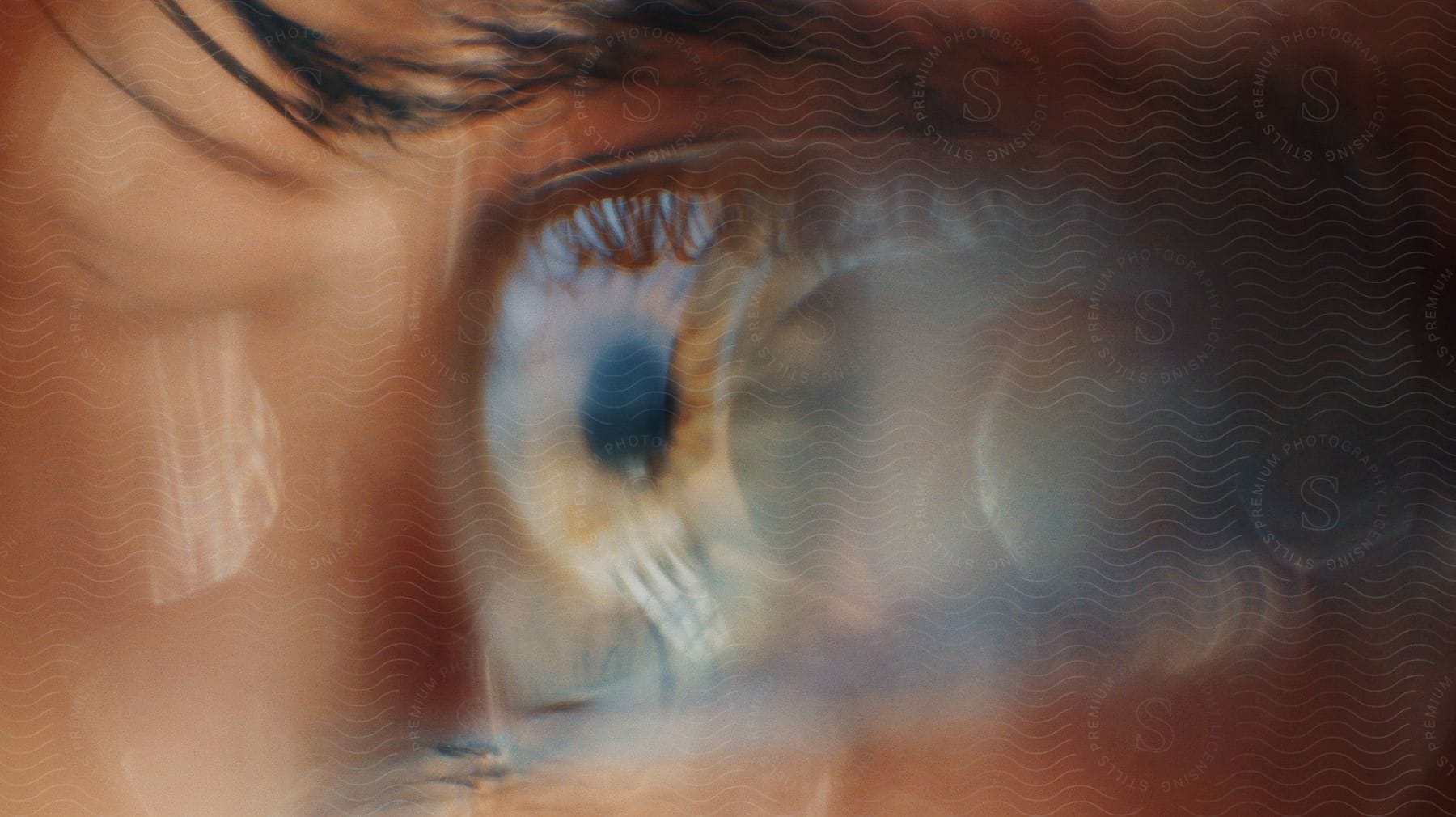 A blurry hazel eye in extreme closeup reflecting brightly in the light