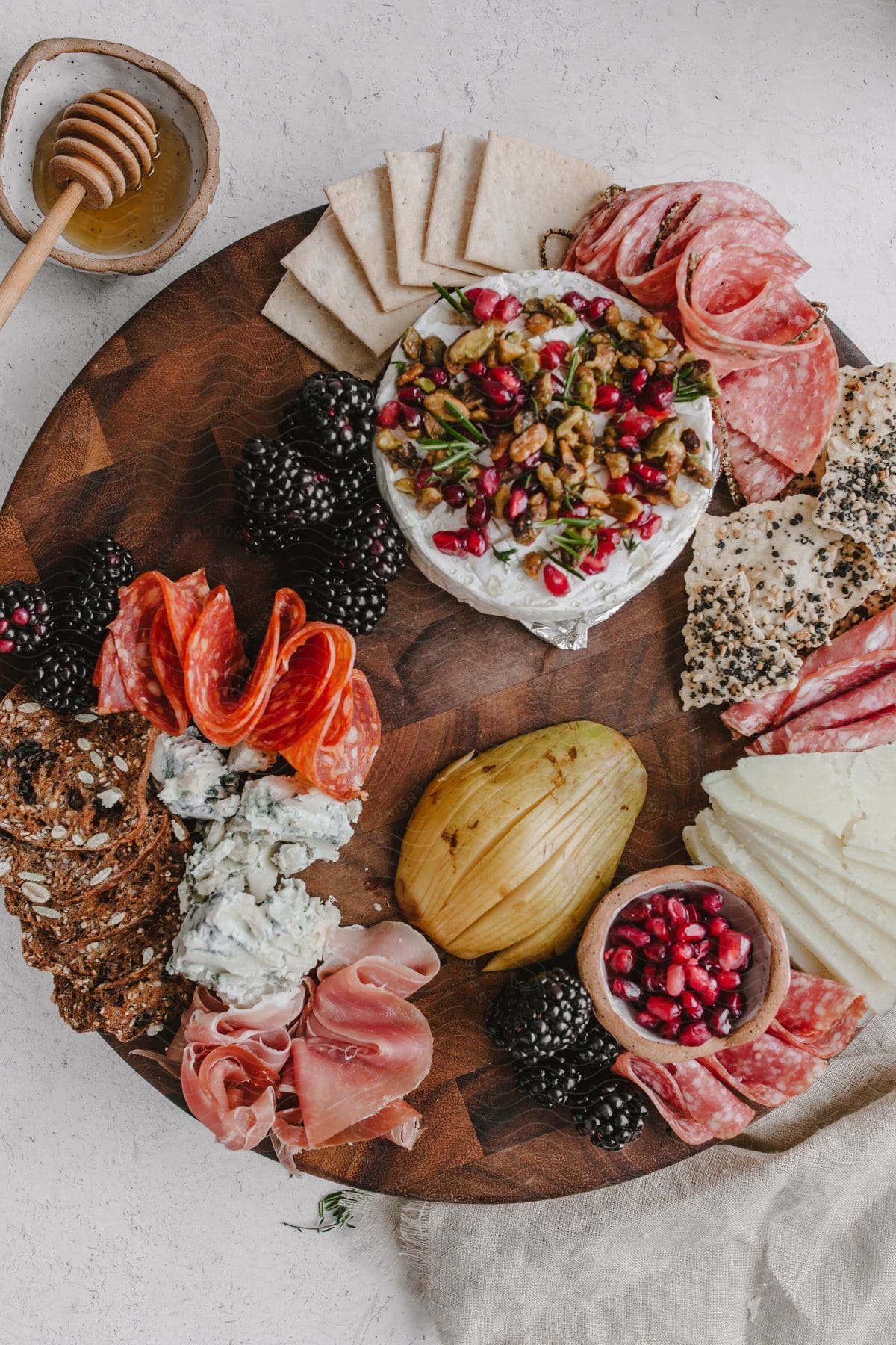 A wooden board with a variety of fruits and cold cuts creating a healthy meal