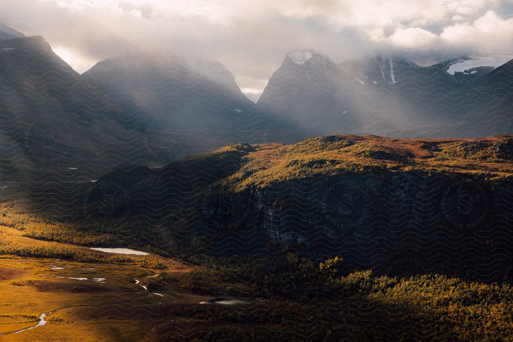 High mountain peaks and lower plains are seen as light peaks through the clouds in the sky