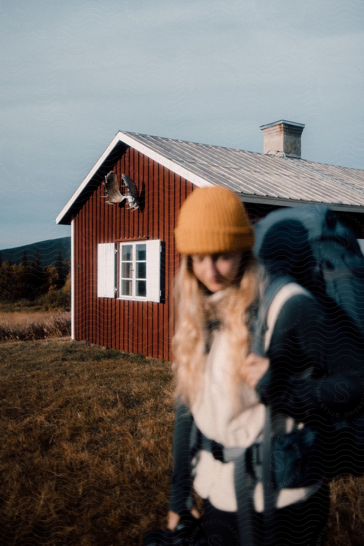 Woman wearing a backpack walking outside of a rural house