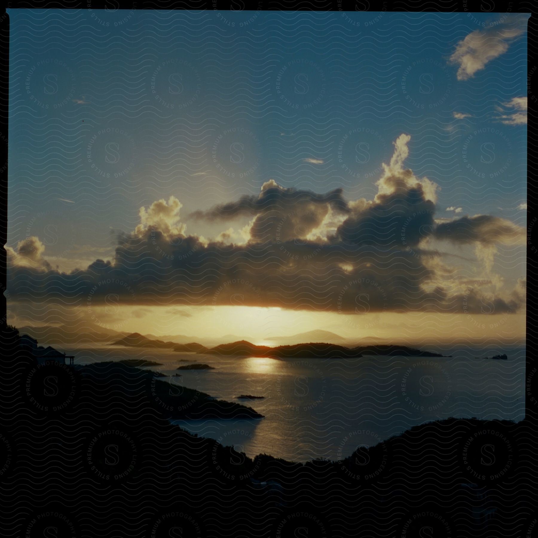 Silhouetted coastline near the sea and small islands at sunset