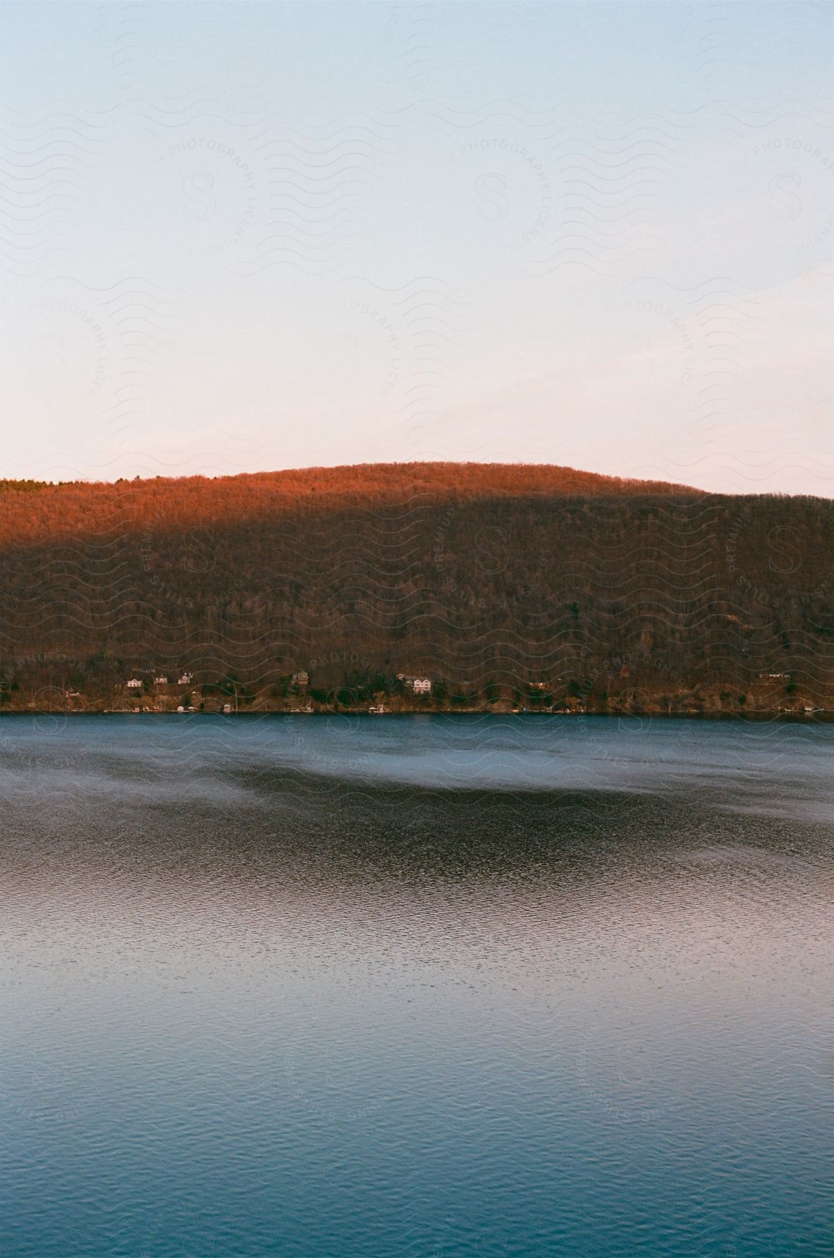 Sunsetsunrise over rolling hills and a lake with houses scattered along the shoreline