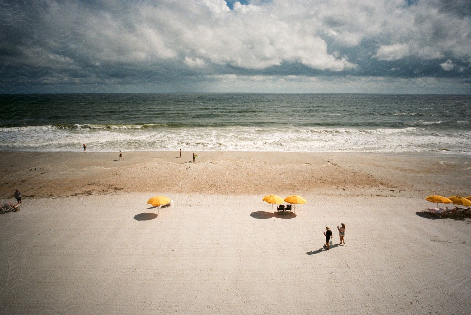 An uncrowded beach with foaming waves and storm clouds in the distance during the day