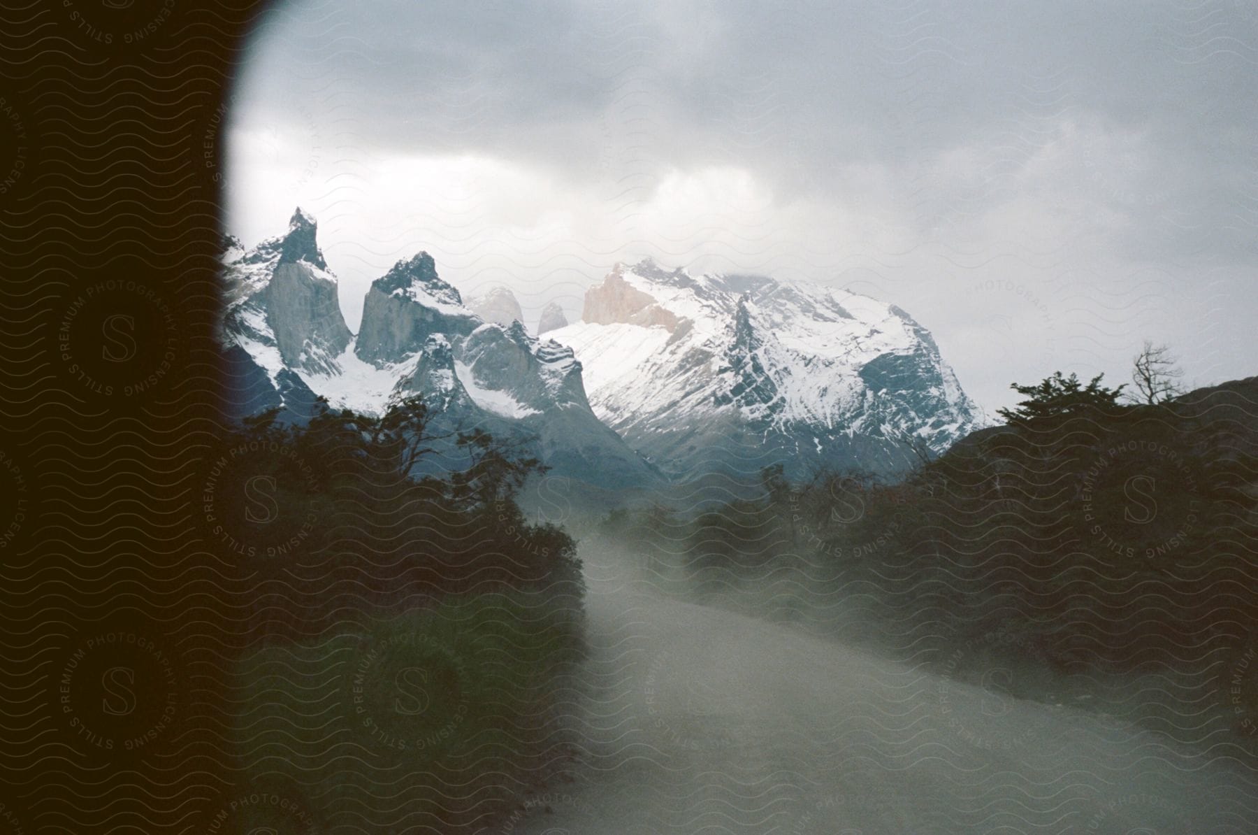 Hills And Snowy Mountains Under A Cloudy Sky In Patagonia