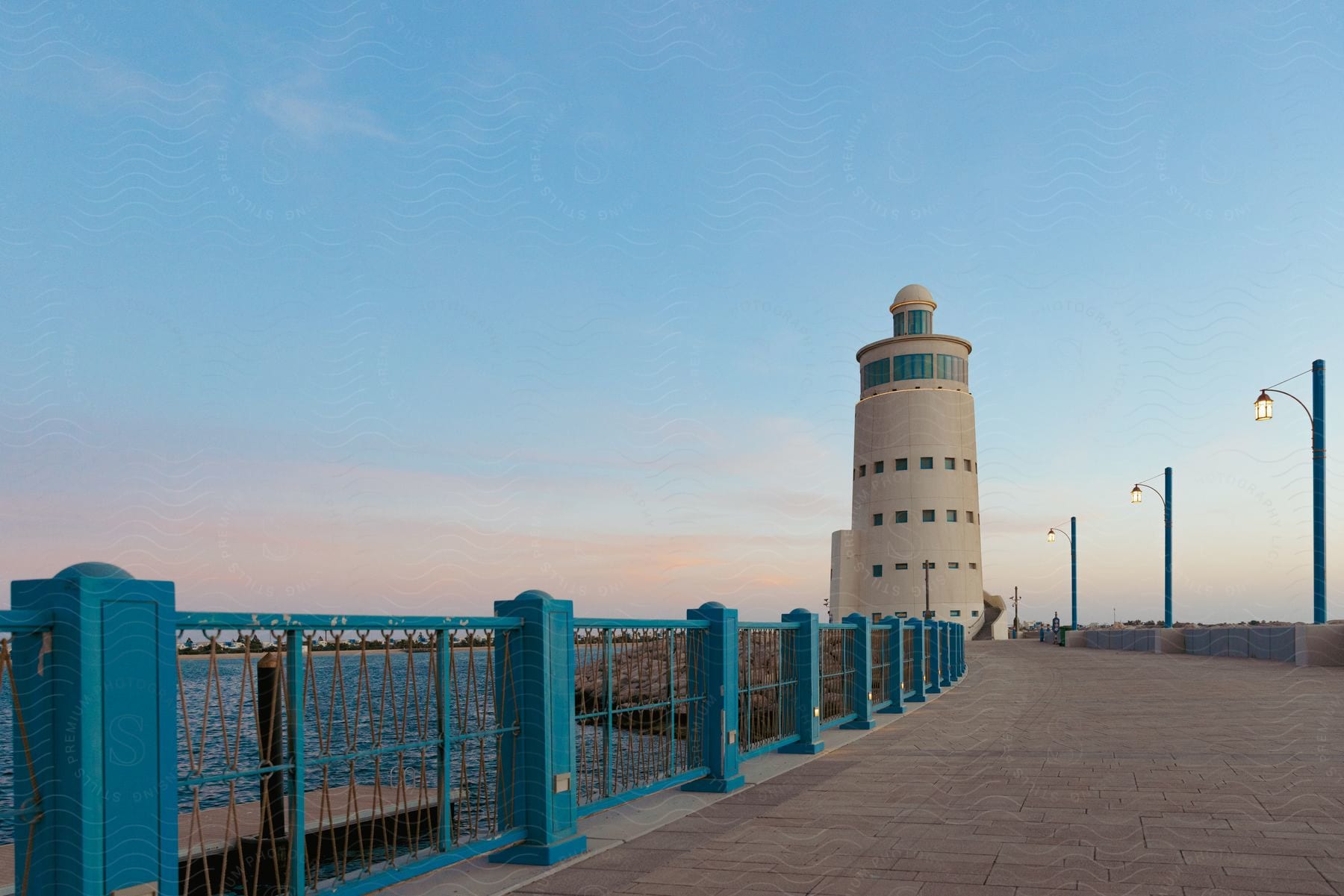 Coastal lighthouse with blue accents brick walkway and blue railing