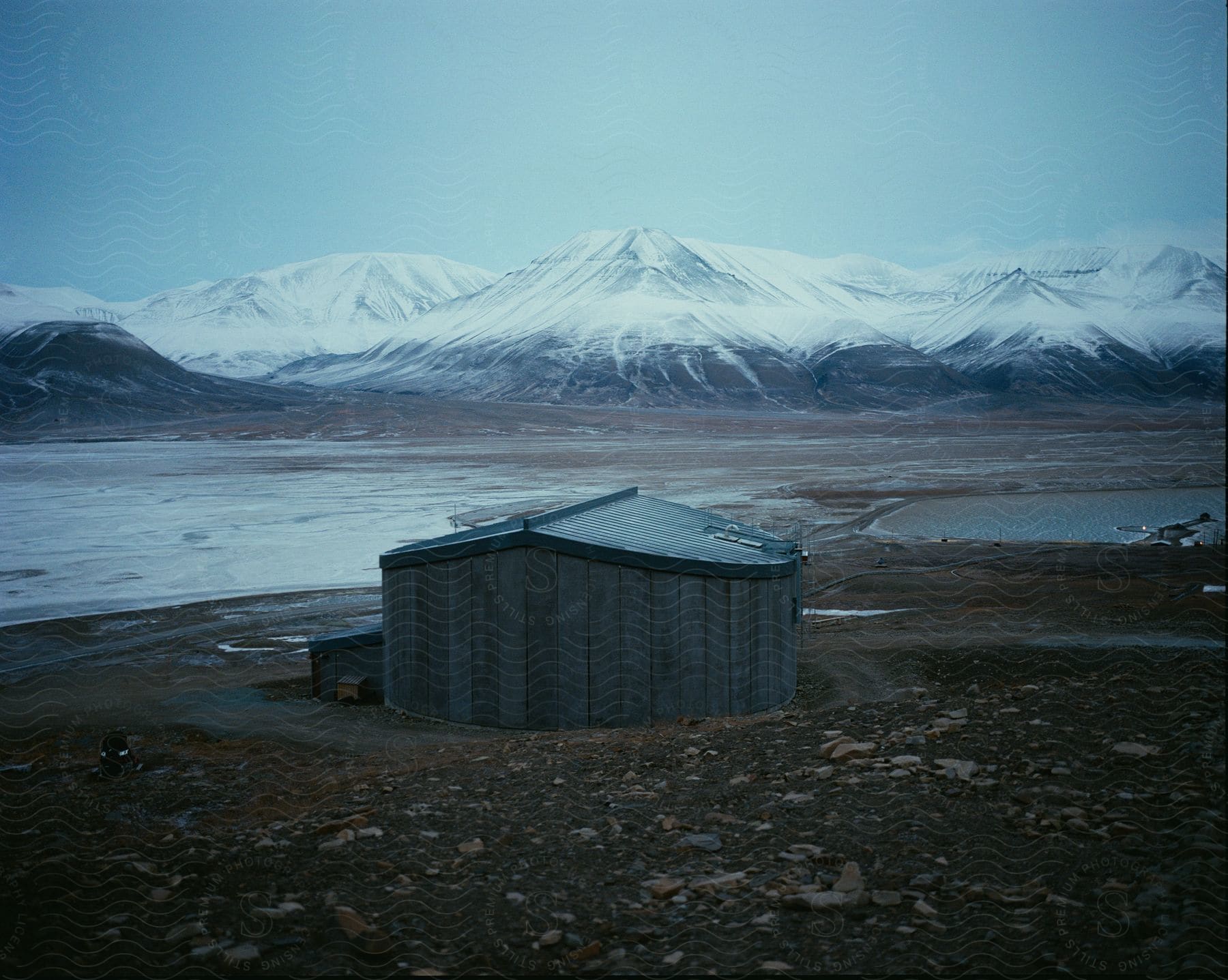 A round hut nestled in rocky terrain surrounded by snowcovered mountains in svalbard norway