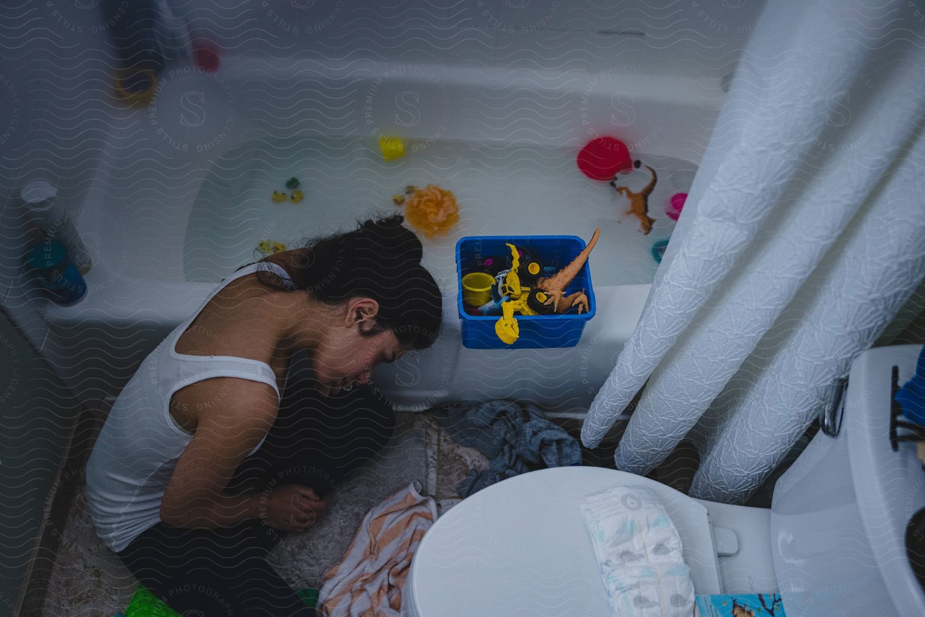 Woman sitting in a bathroom with childrens toys scattered around