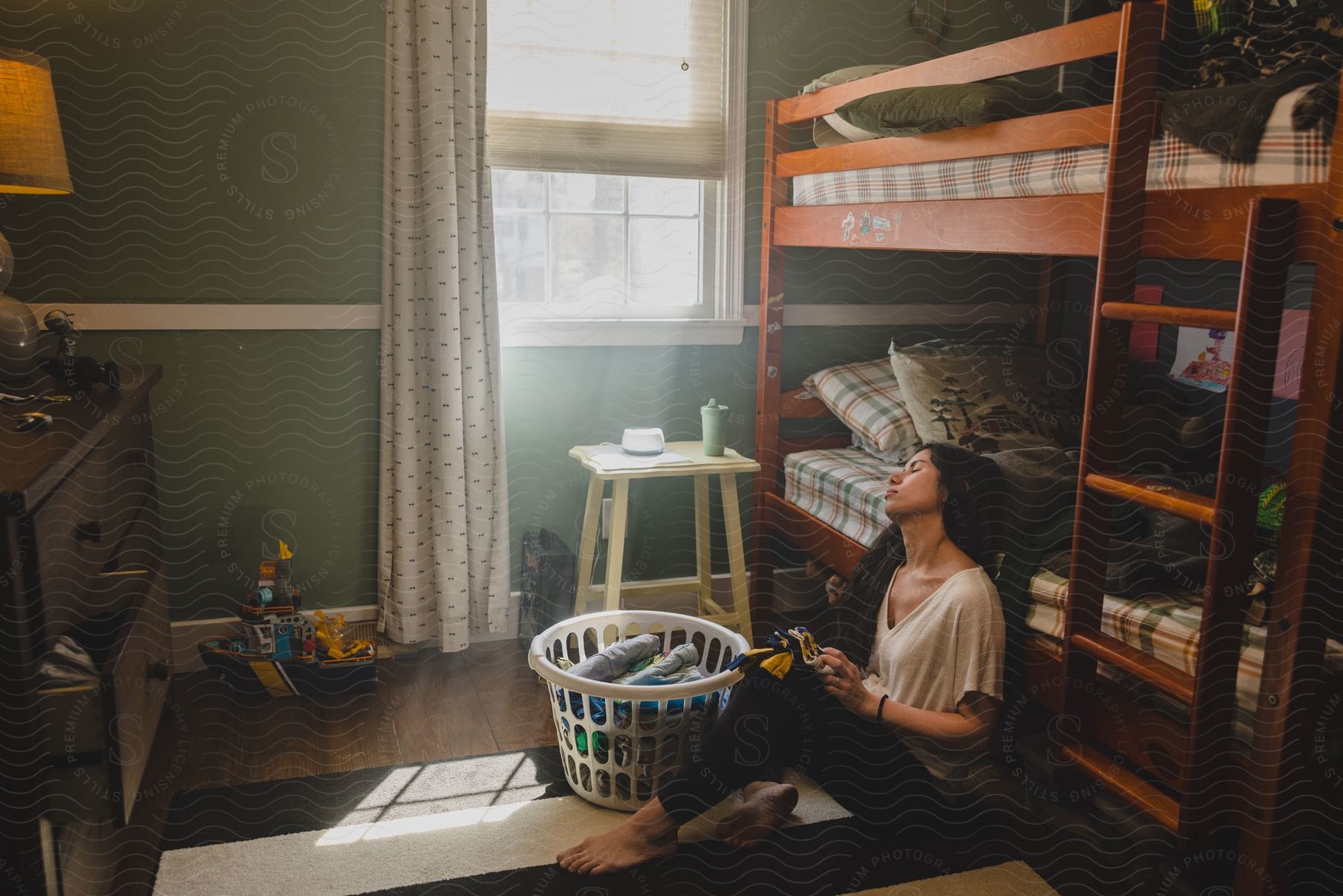 Young woman folding laundry on the floor of the bedroom during the day