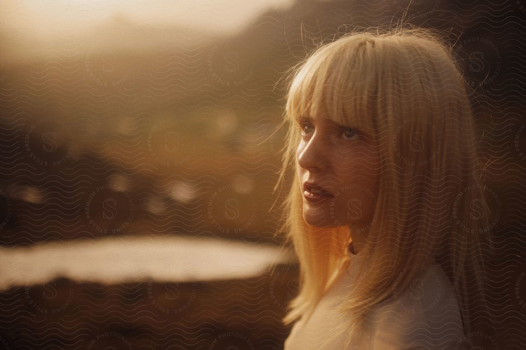 One young adult woman with blonde hair in a field with sunlight and a flash