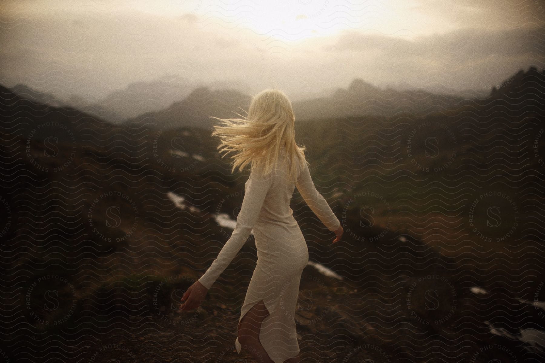 A woman standing outdoors in the wilderness during dusk or dawn