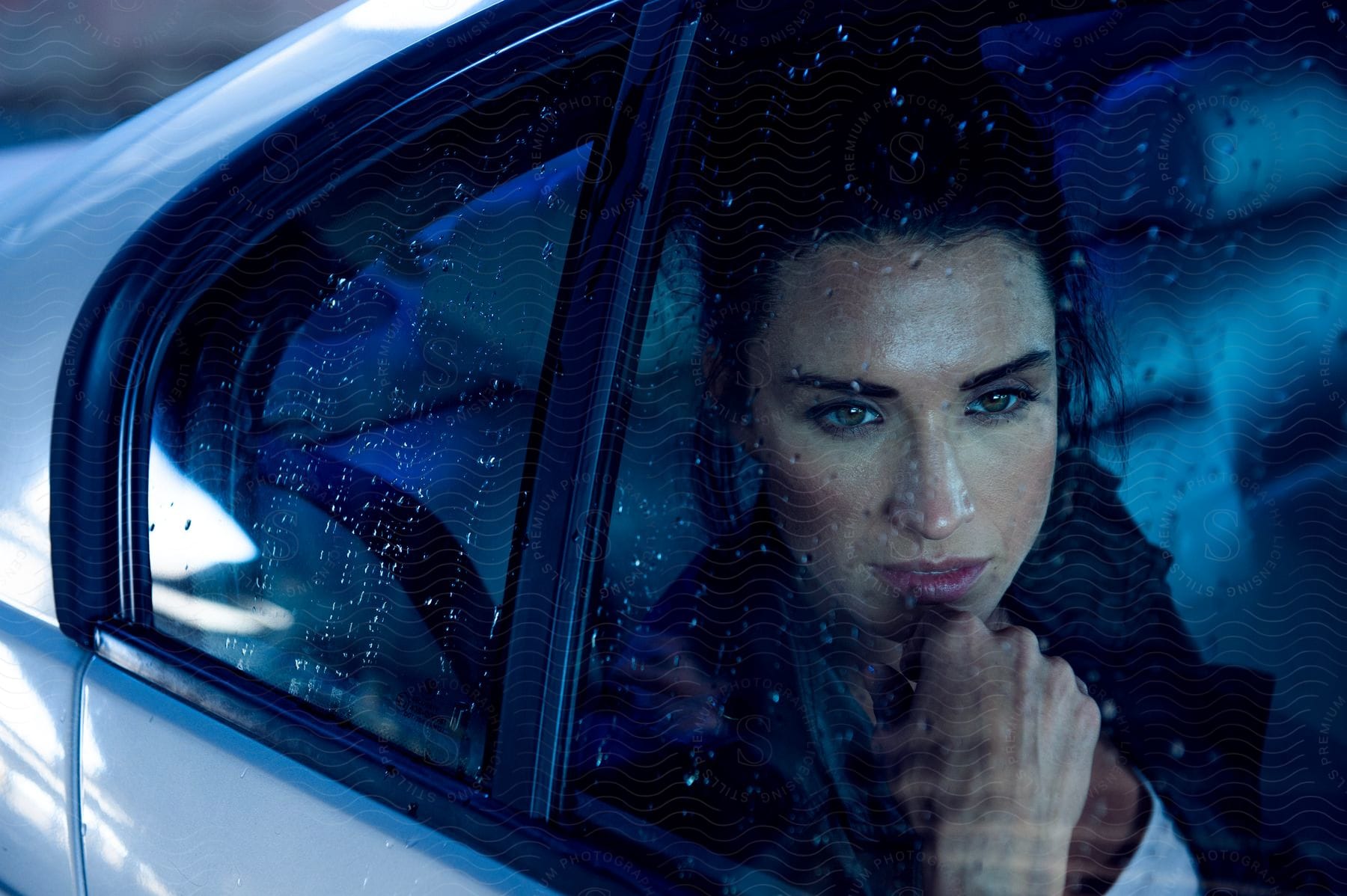 A woman in a car looks out at the rain