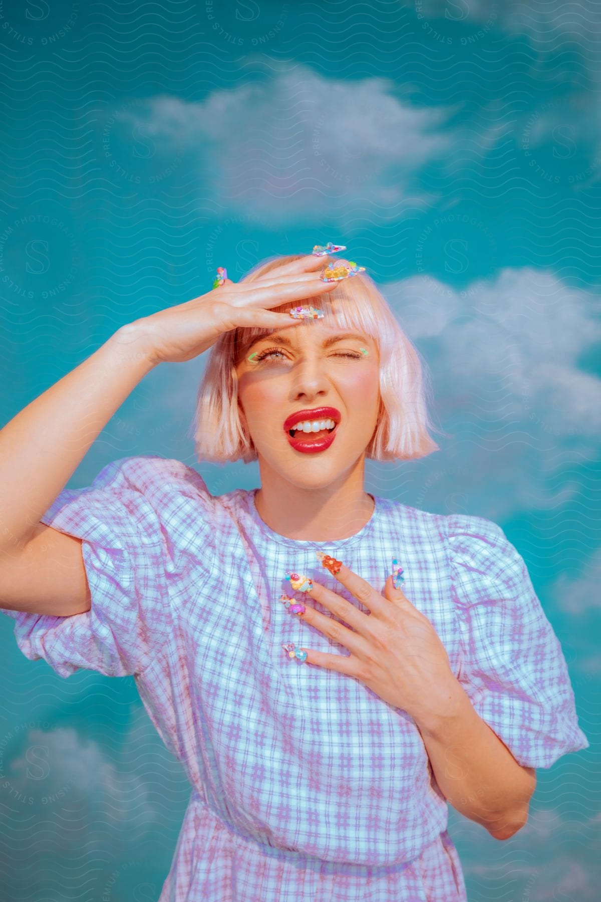 A woman in a summer dress and colorful nail decorations poses for a photo