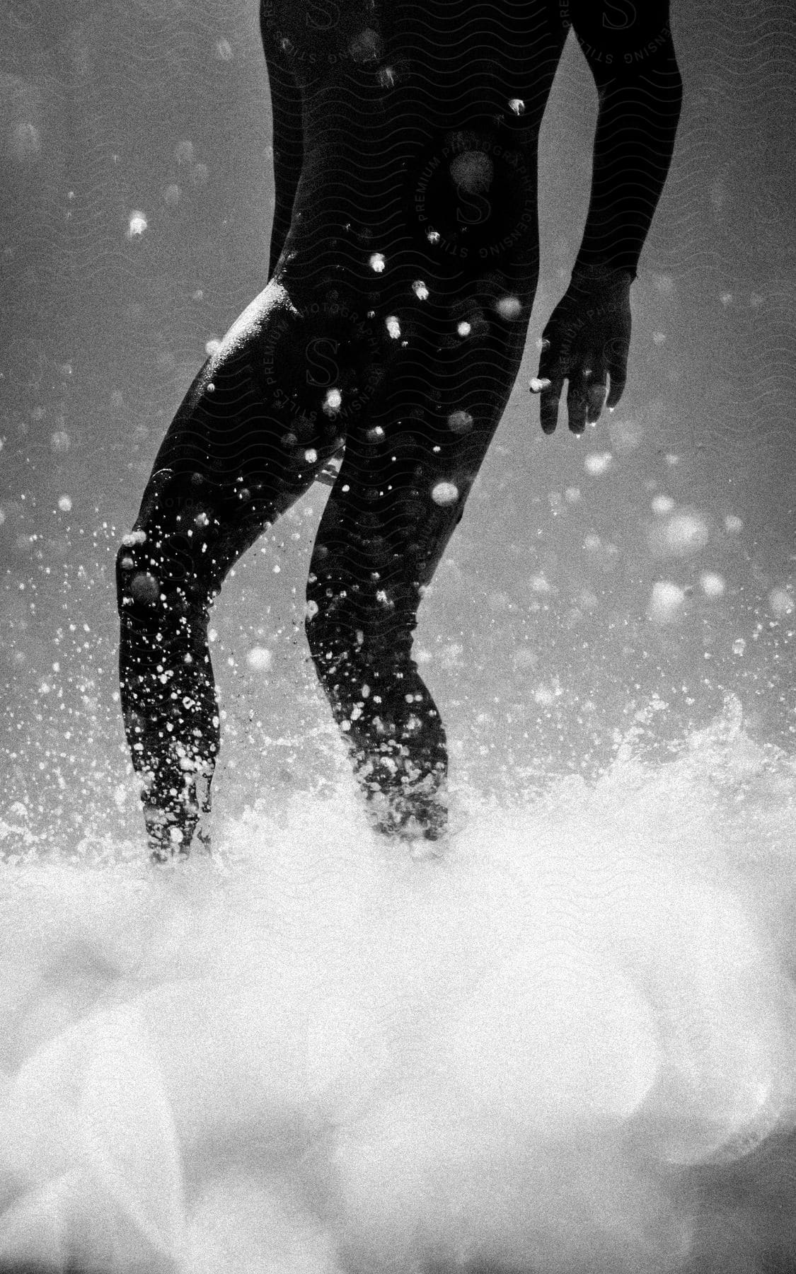 Stock photo of a person wearing all black is shown from the chest down standing in water.