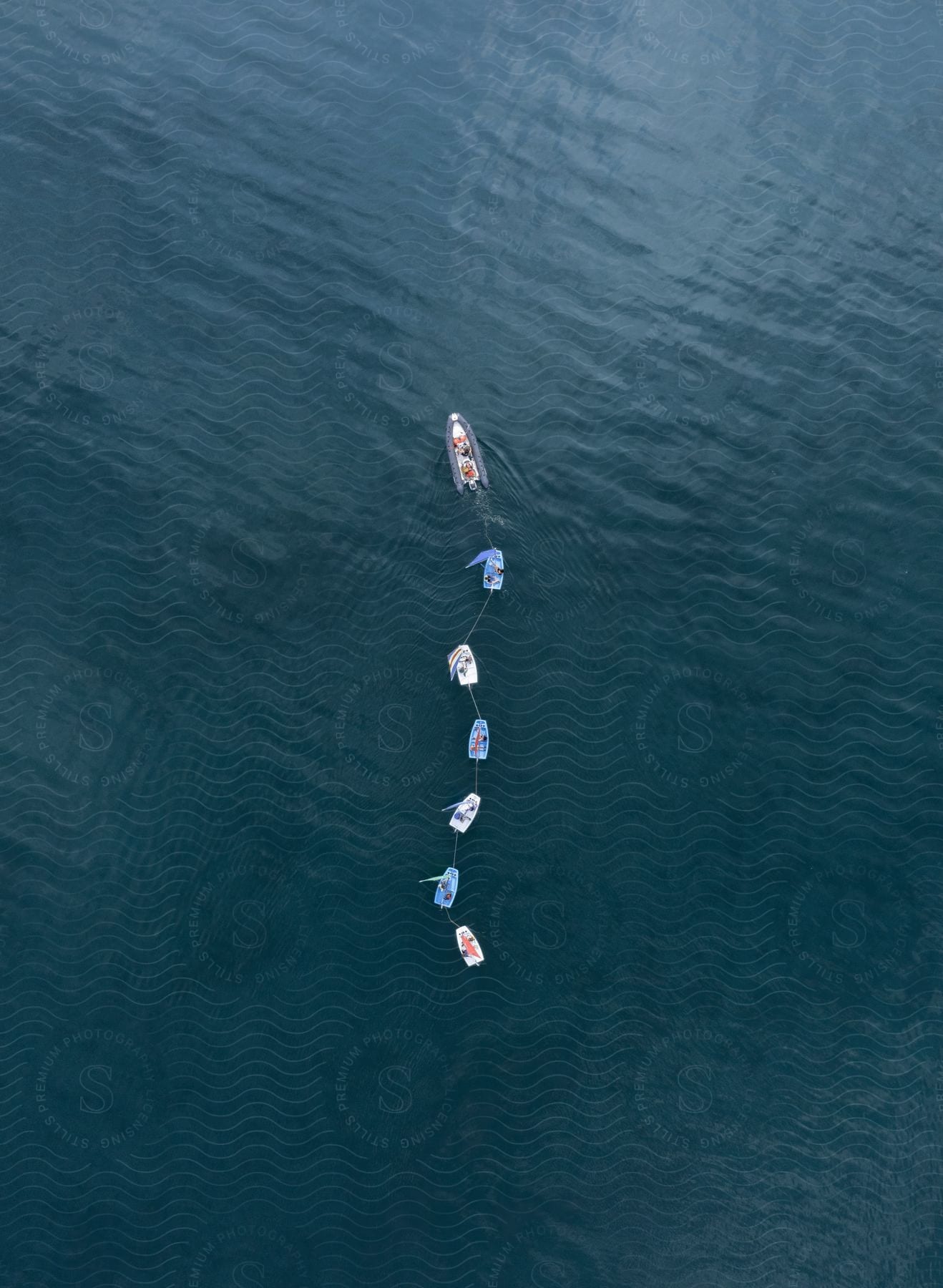 Large boat towing six smaller boats in a lake