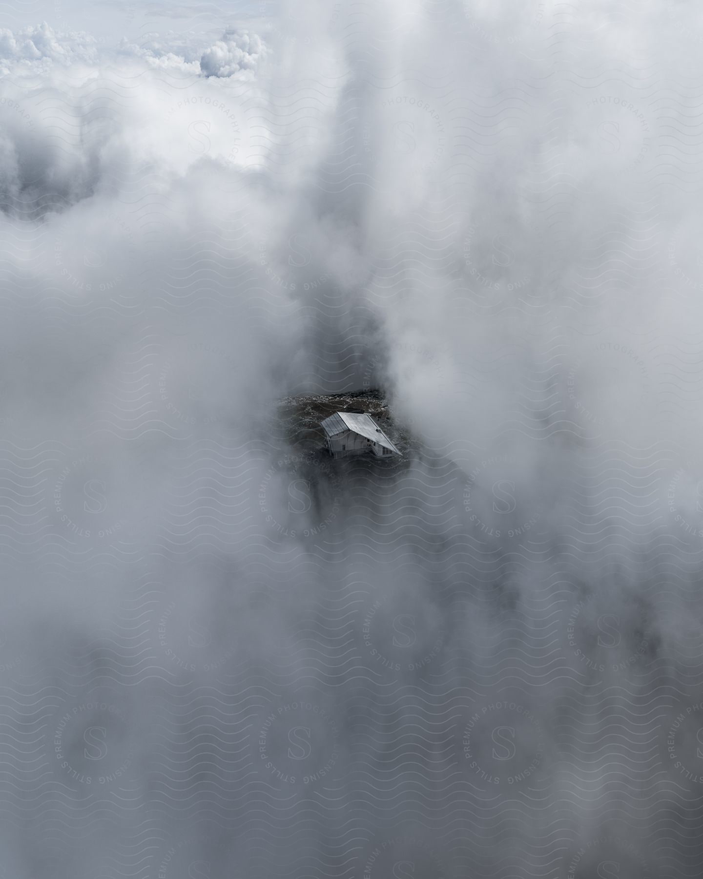 A house in the countryside seen through a hole in the clouds from an aerial perspective