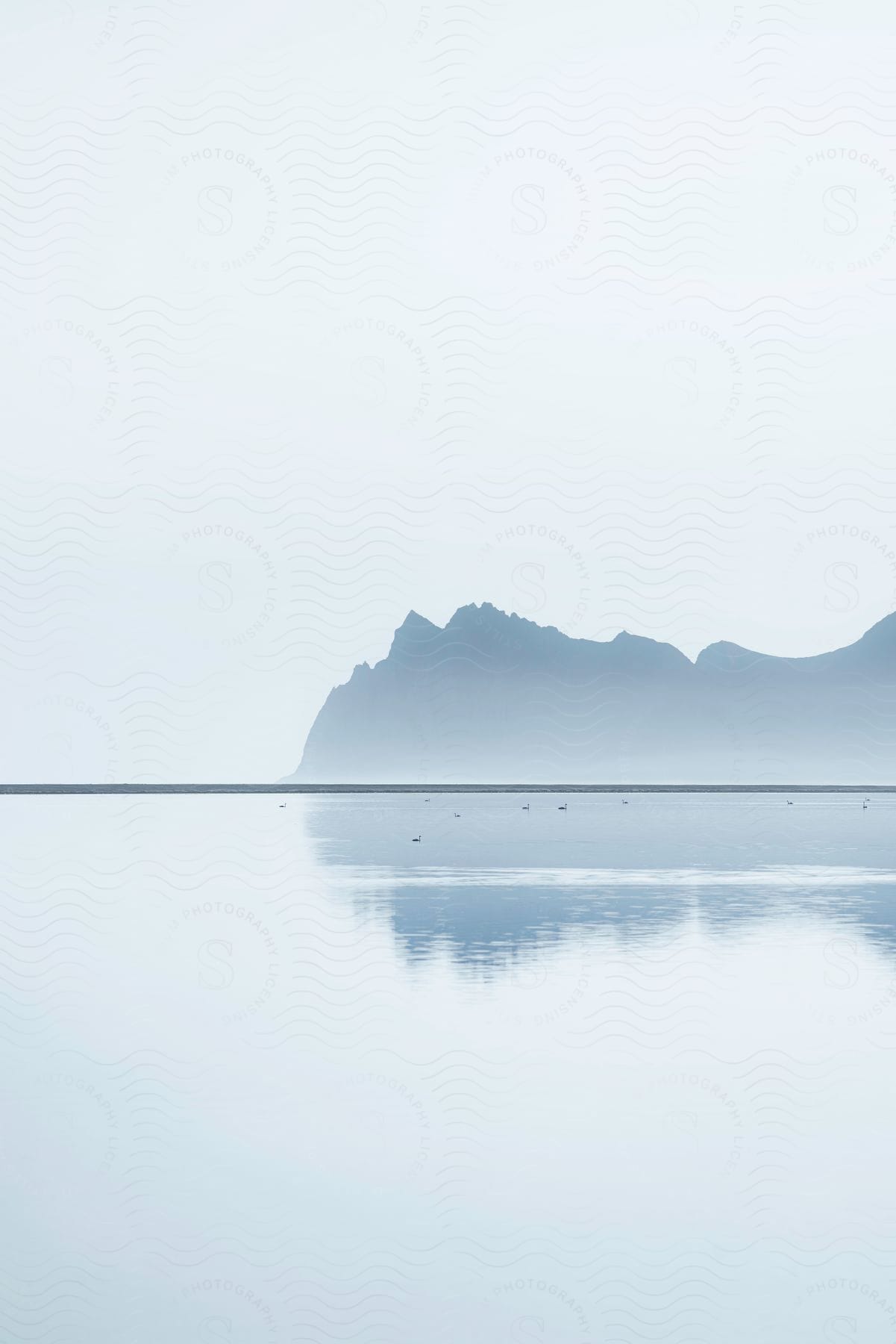 A lone mountain in the mist surrounded by a lake.