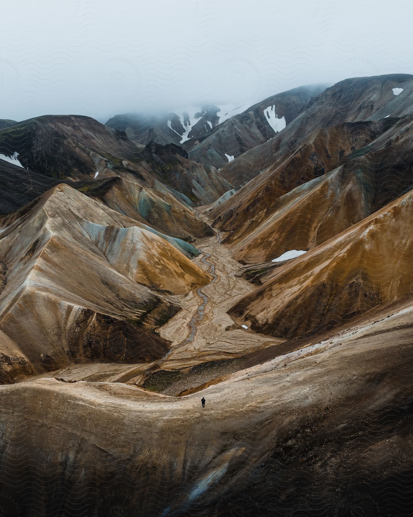 The silhouette of a single hiker at the base of the Landmannalaugar rainbow mountains in Iceland