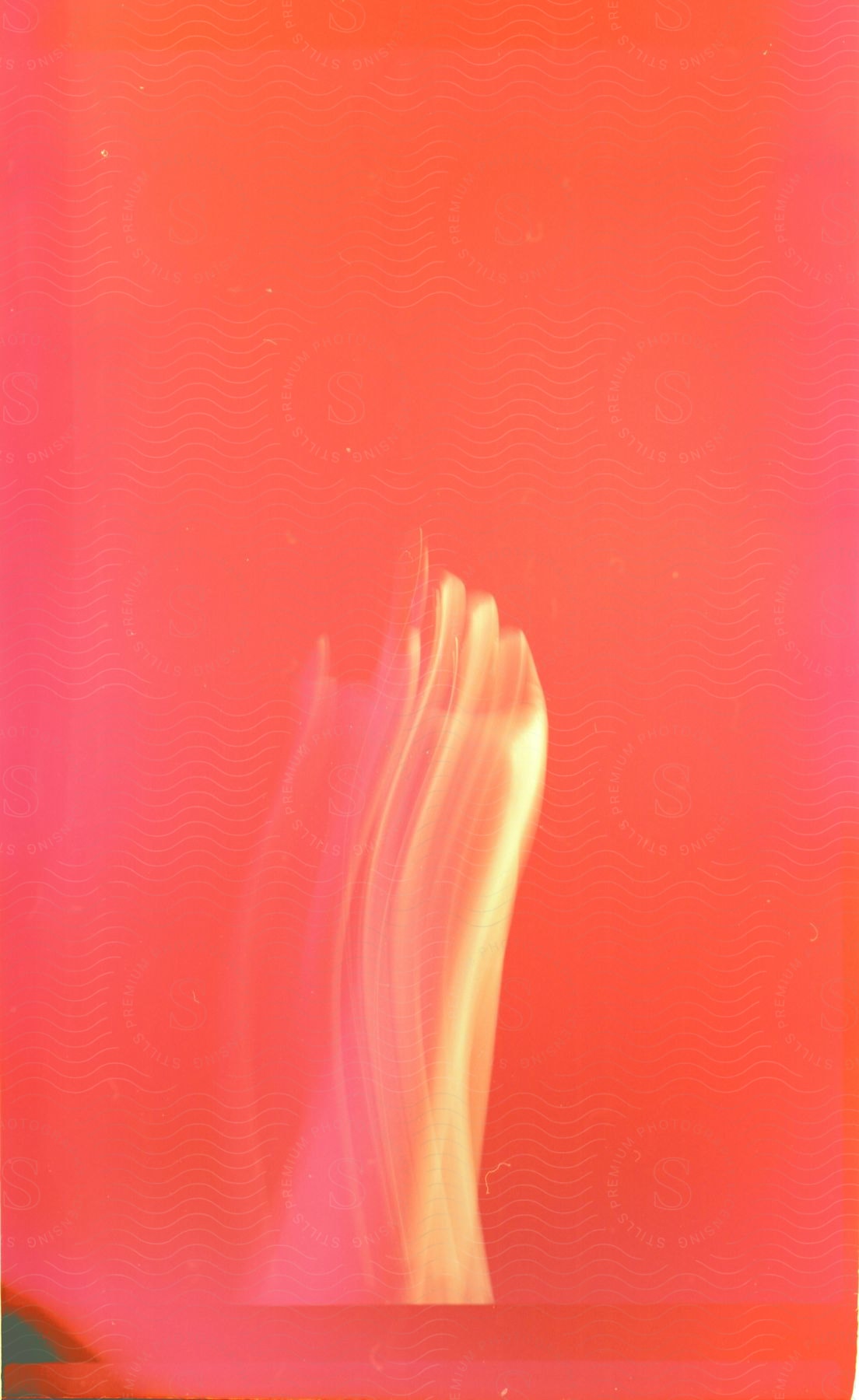 Blurred Human Hand Under Strong Light Against A Red Background