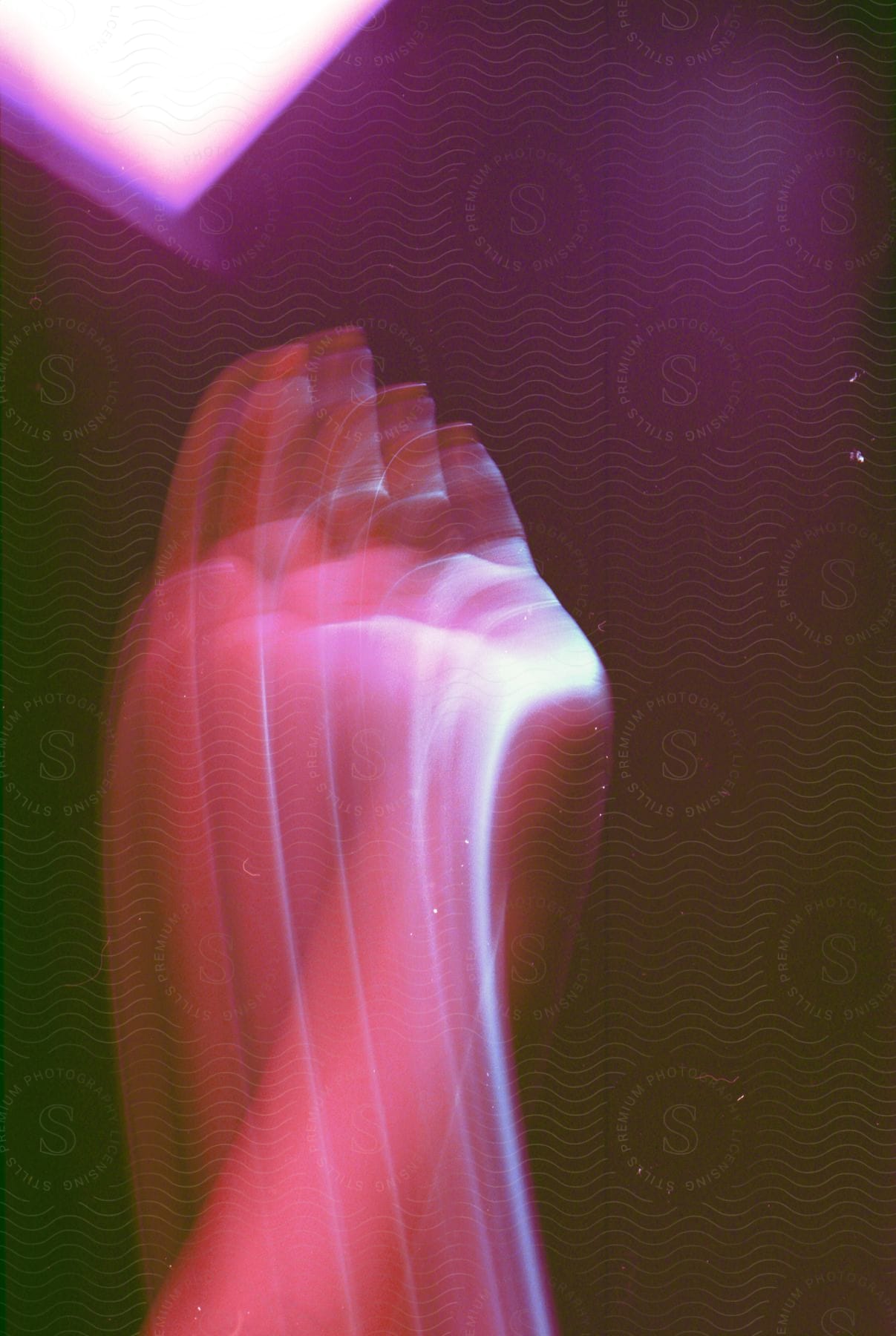 Blurred hand moves under led light creating visual effect and mystery