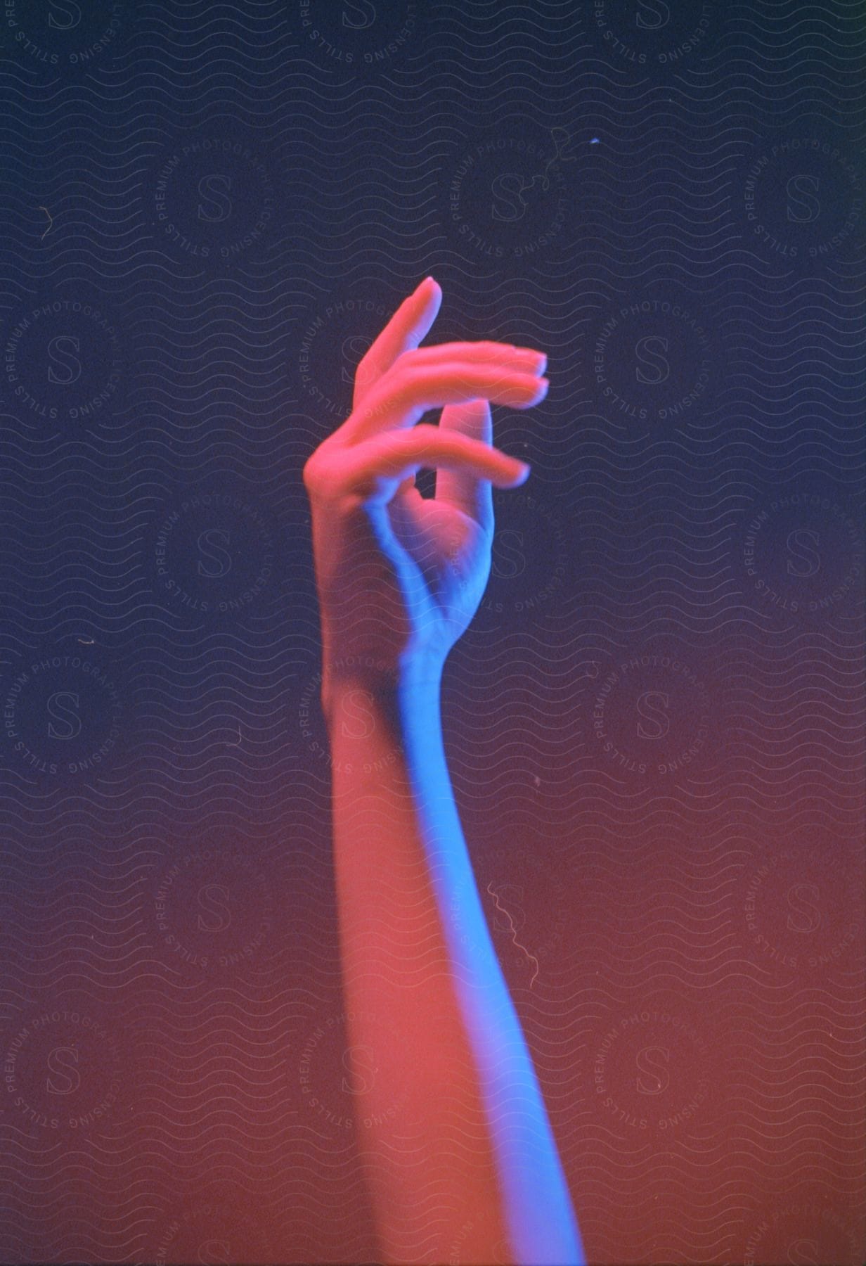 A hand gesturing against intense red and blue lights and textures