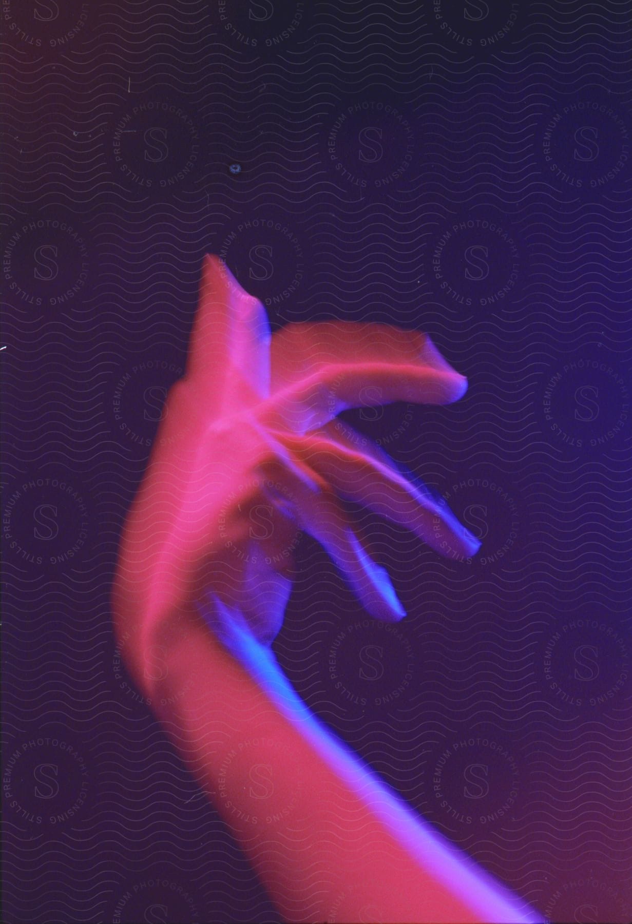 A persons hand making a gesture with purple lighting effects