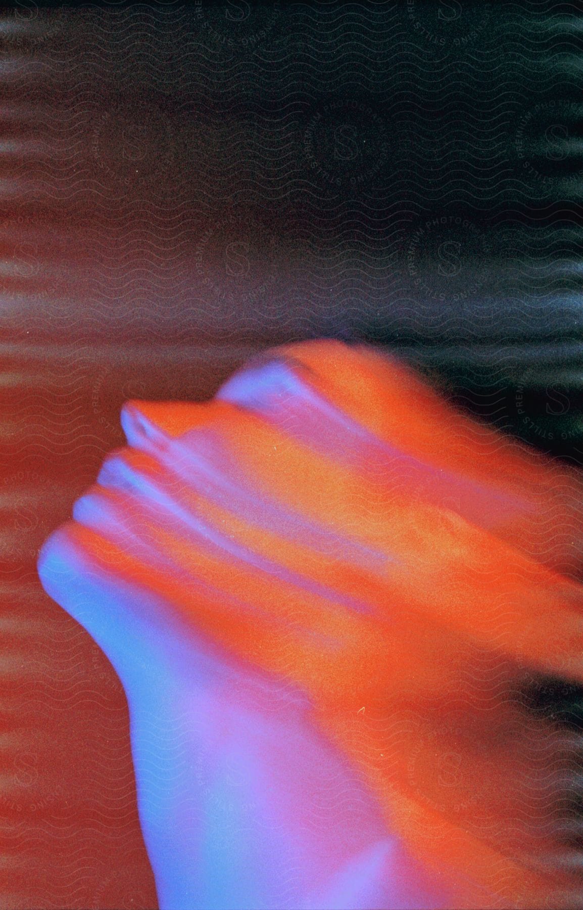 Close up of a womans blurred face in bright orange and electric blue lights