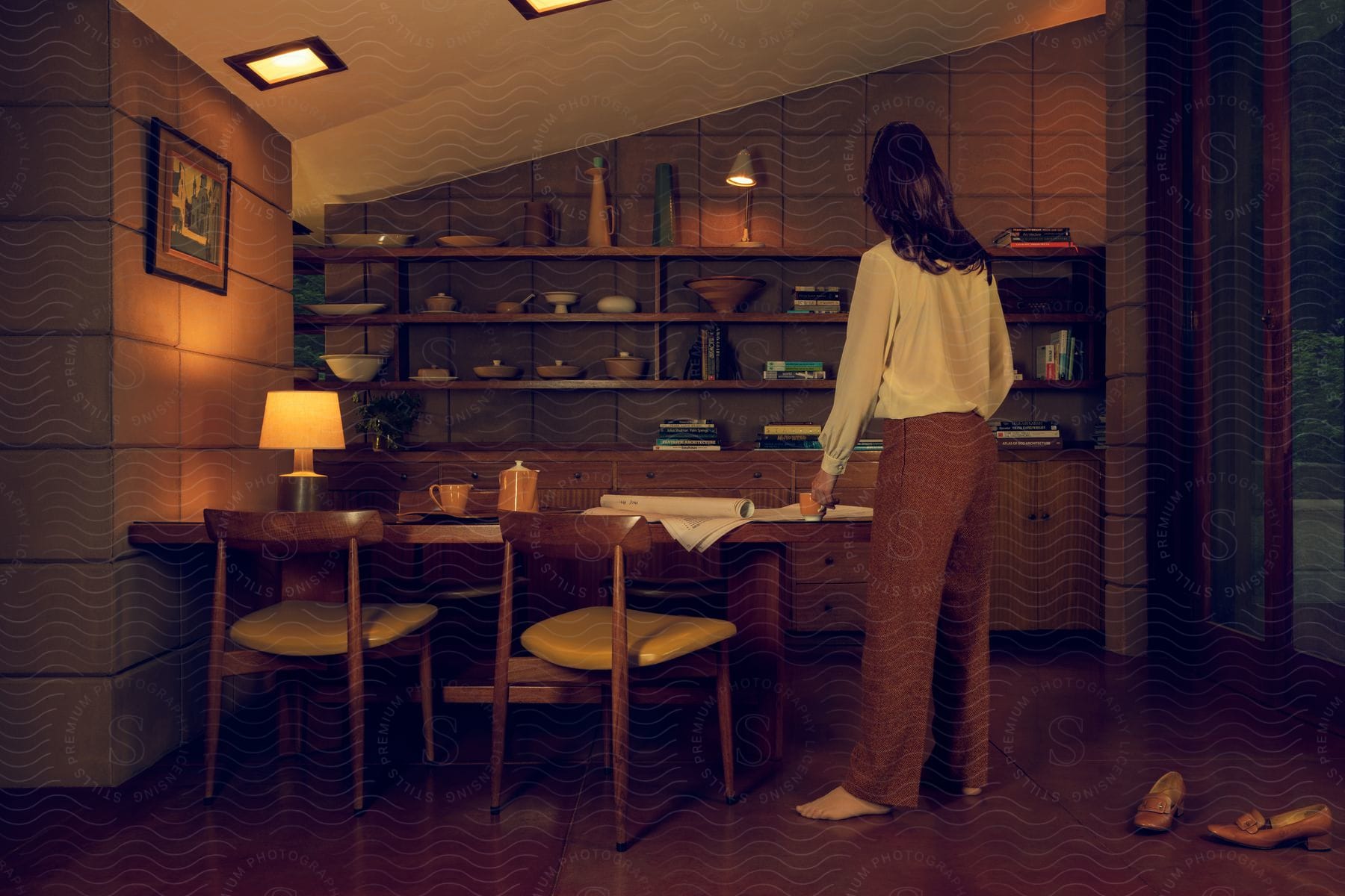 Stock photo of a shoeless woman stands in her living room looking at architectural drawings