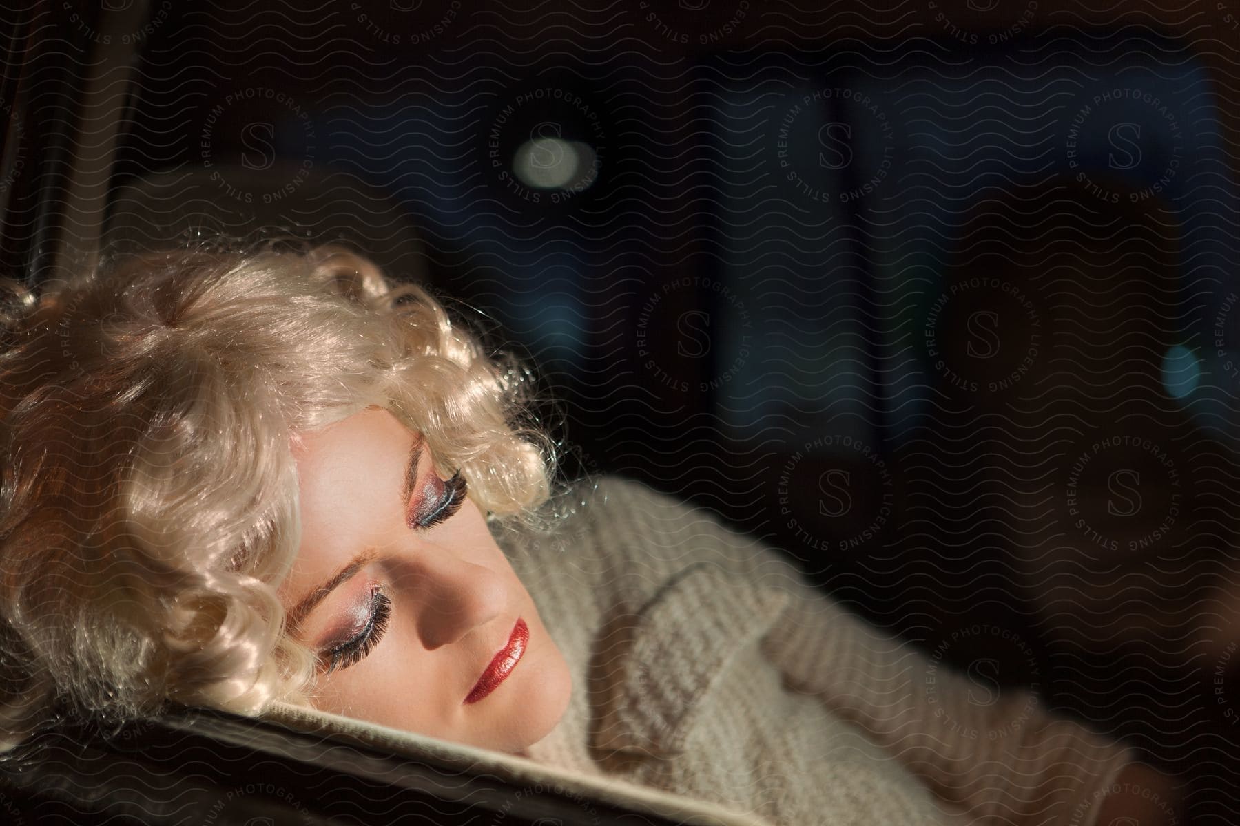 Blonde woman asleep inside a car at night