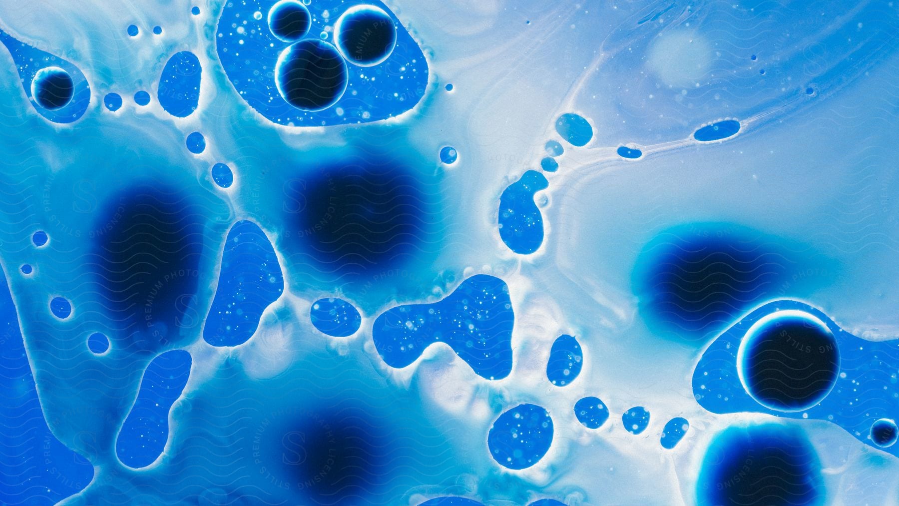 Clusters Of Small Bubbles Are Interspersed With Larger Dark Liquid Droplets Suspected Atop A Blue Liquid