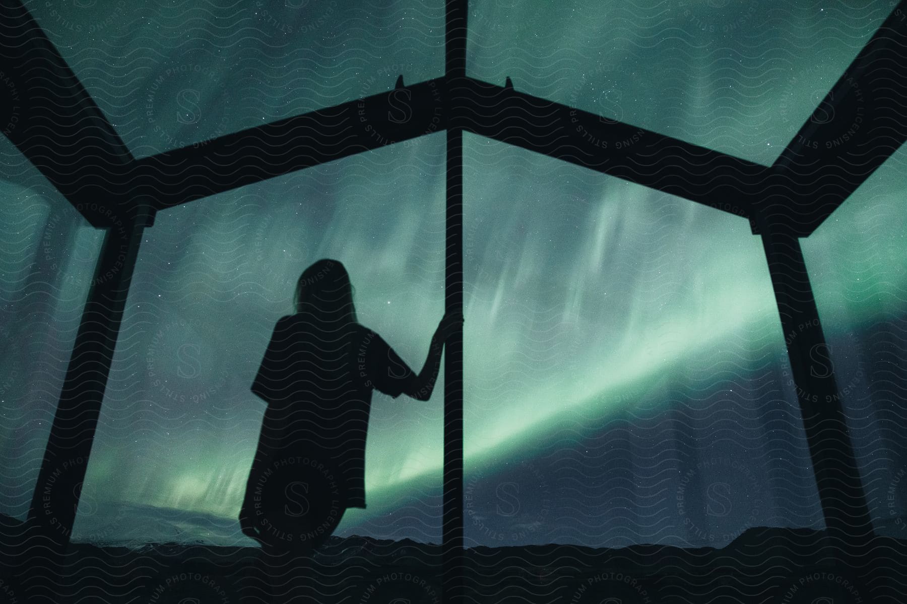 Stock photo of a woman observes the aurora borealis at night