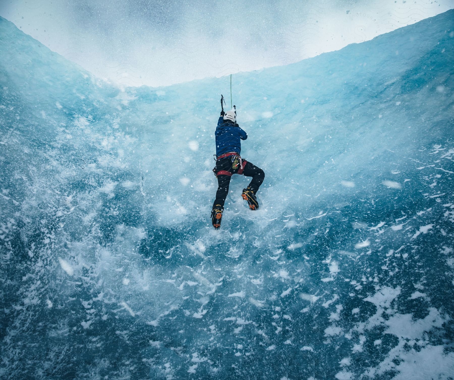 A rock climber ascending a frozen cliff