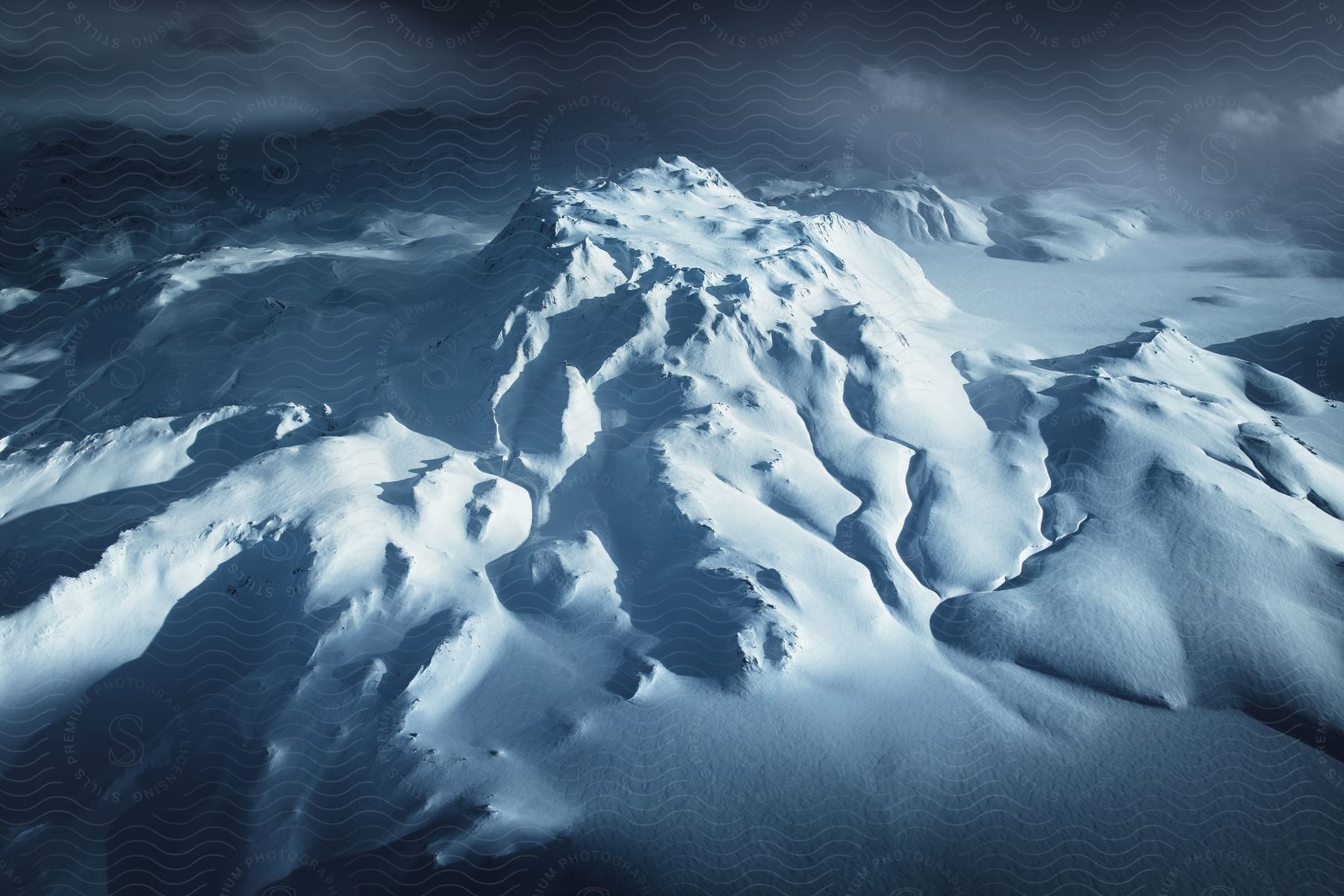 Cloud rolling across snowcovered mountain top in the arctic