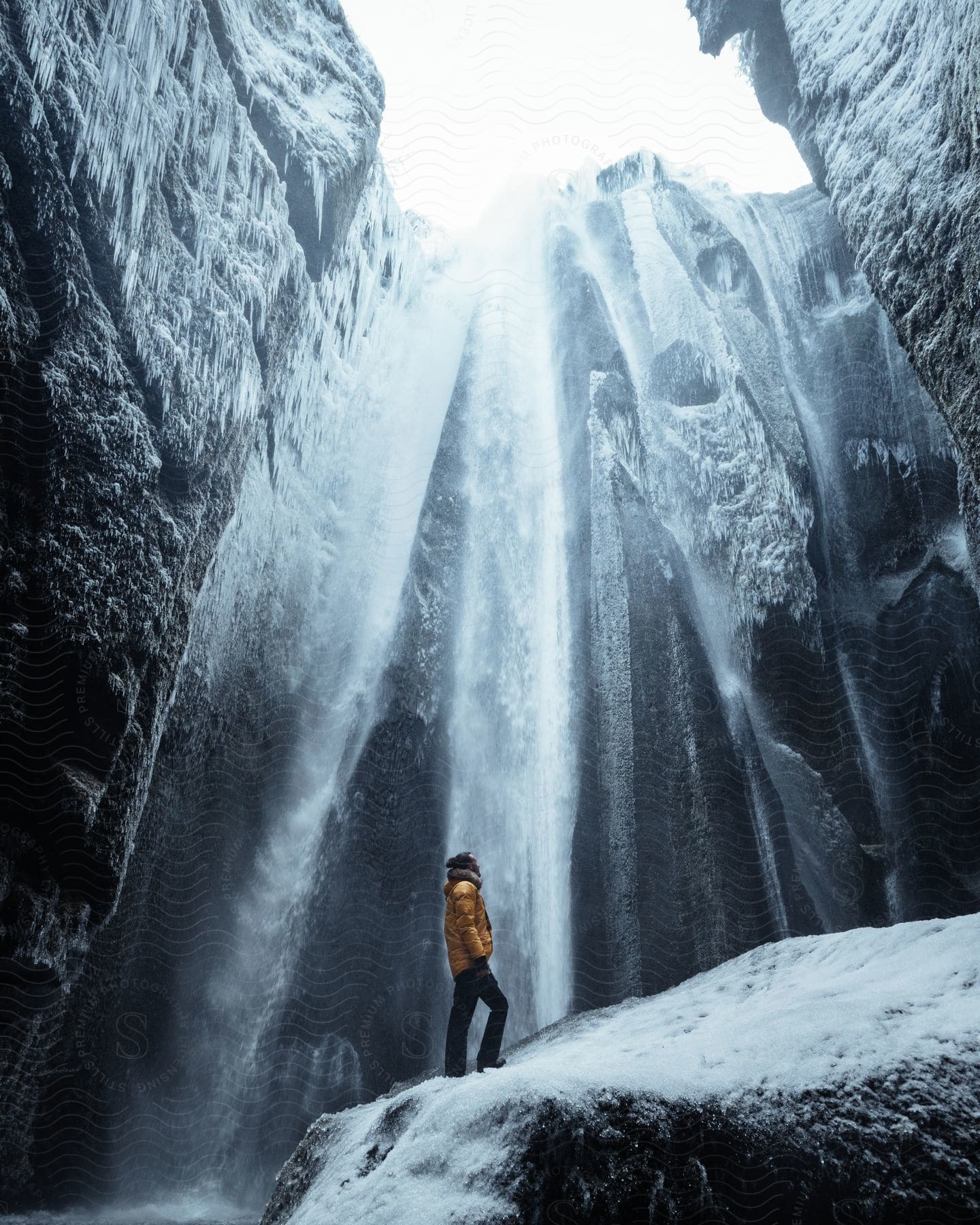 A man stands under an icy waterfall in iceland